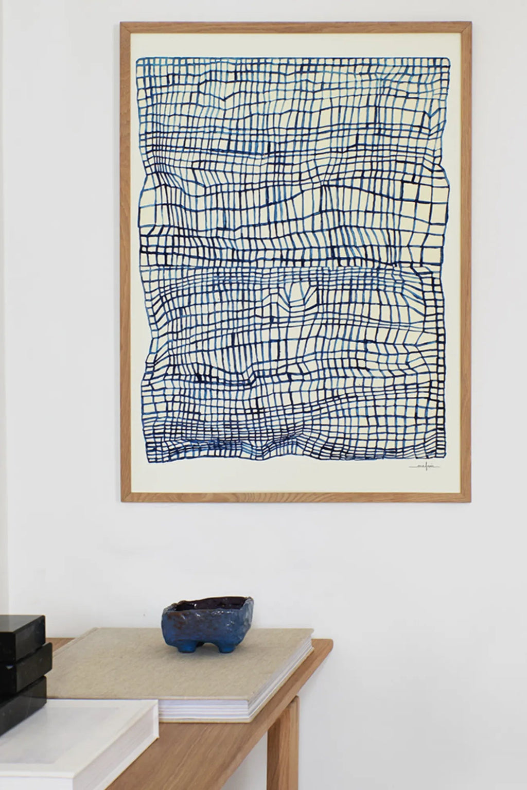 The Poster Club Sketchbook, a modern abstract art print featuring an organic, hand-drawn wavy grid pattern in rich deep blue tones against a warm off-white background, framed in a light natural oak frame.