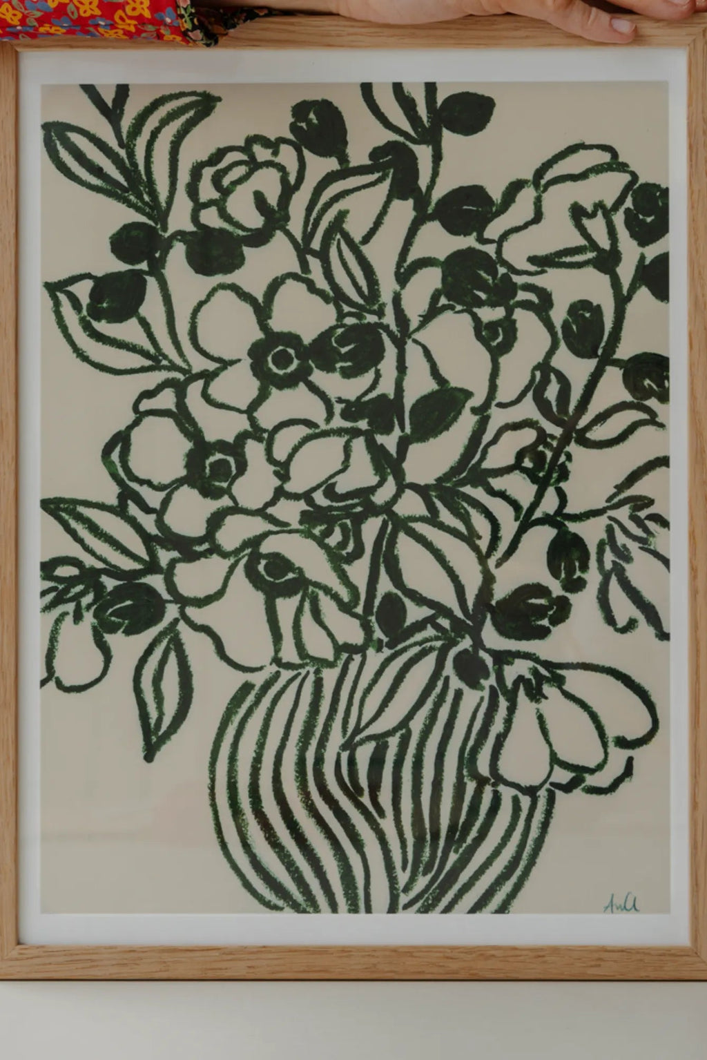 The Poster Club Poppy Studies II, a modern botanical art print showcasing hand-drawn dark green poppy flowers and leaves with a textured, chalk-like finish, gracefully arranged in a striped vase against a soft off-white background. This minimalist floral design is elegantly framed in a light natural oak wood frame, perfect for adding an organic modern touch to contemporary living rooms, bedrooms, or gallery walls.