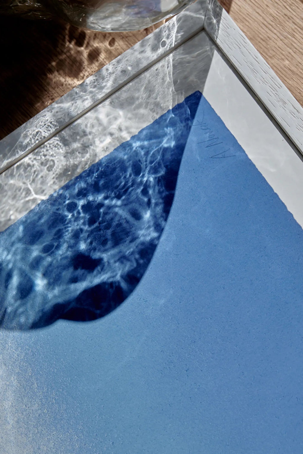 The Poster Club Blue Interstellar, an abstract art print featuring a vibrant deep blue, matte-textured surface and an organic, fluid shape, housed in a light natural wood frame with a white mat.