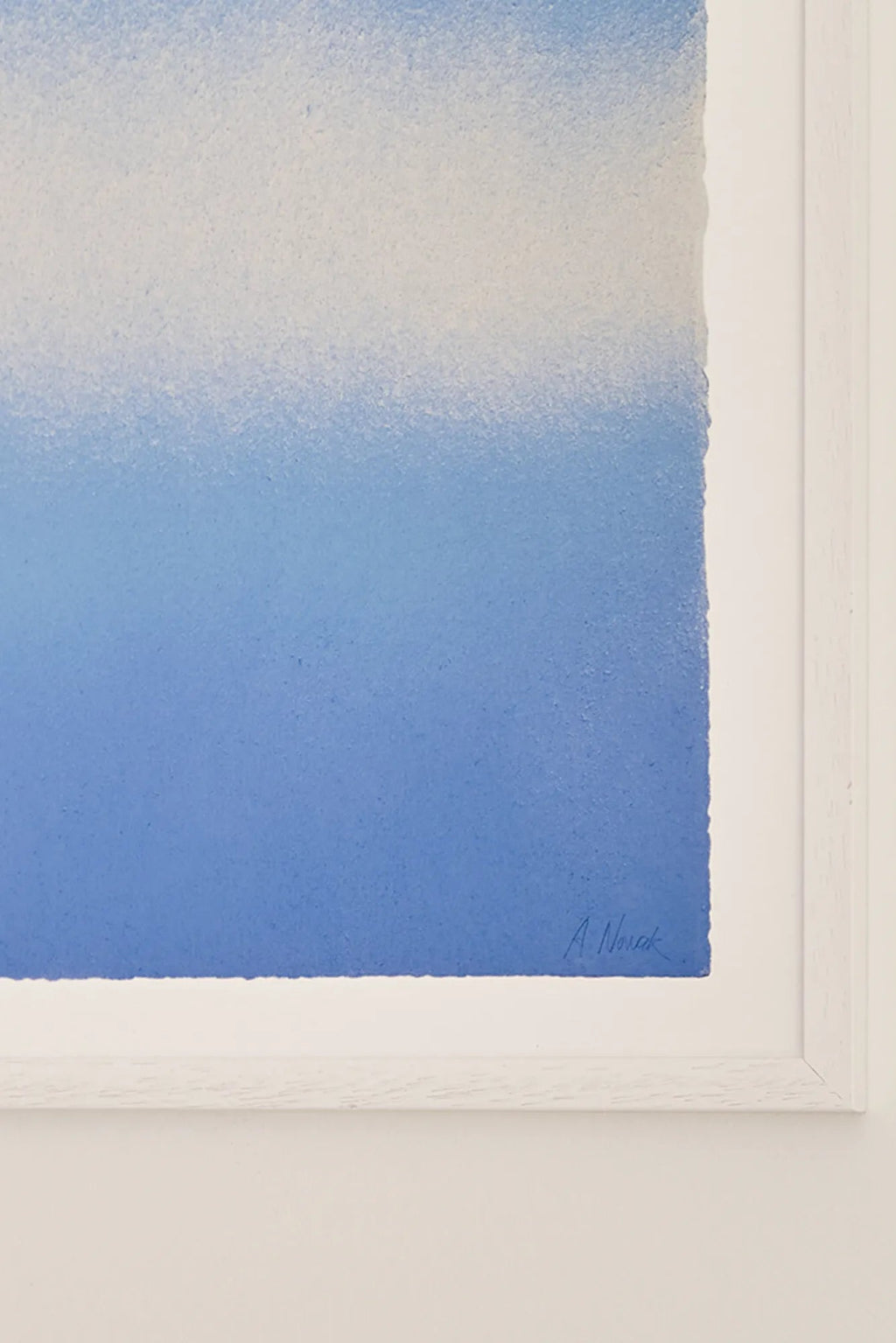 The Poster Club Blue Interstellar, an abstract art print featuring a soft blue and white gradient transitioning to a rich royal blue, with a subtle grainy texture and deckled edges, presented in a crisp white wood frame. This minimalist color field poster offers a serene touch for contemporary gallery walls, Scandinavian living rooms, or modern bedrooms.