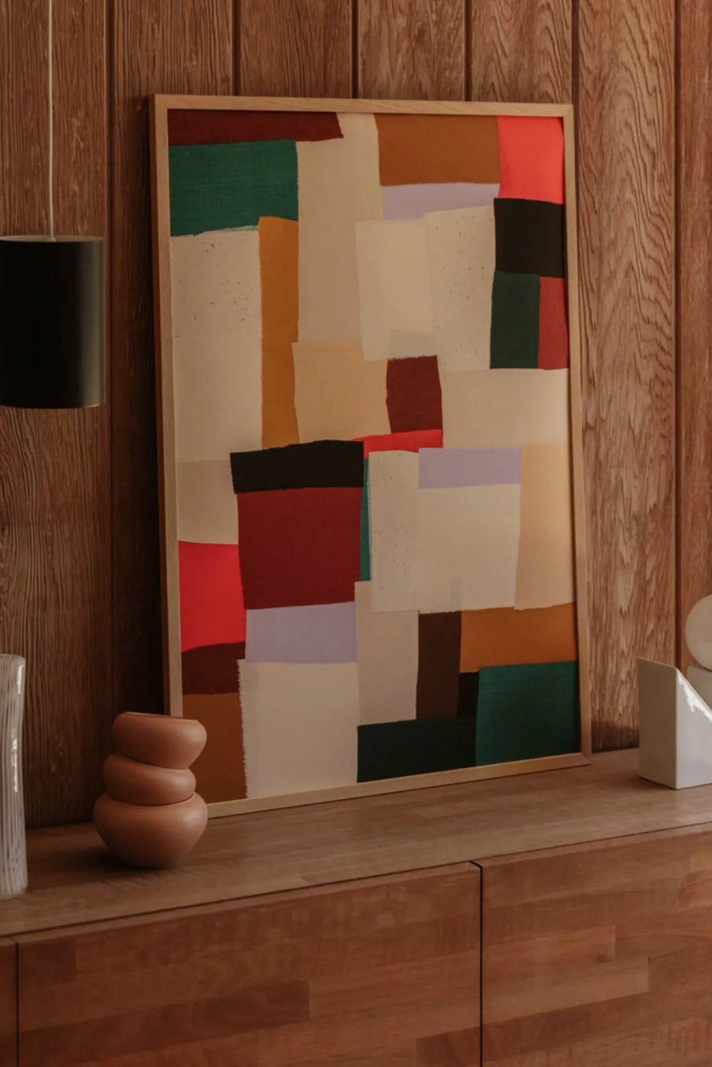 The Poster Club Fields, a vibrant abstract art print featuring a collage of colorful blocks and patches in shades of cream, beige, mustard yellow, dark red, bright red, deep green, black, and soft purple, presented.