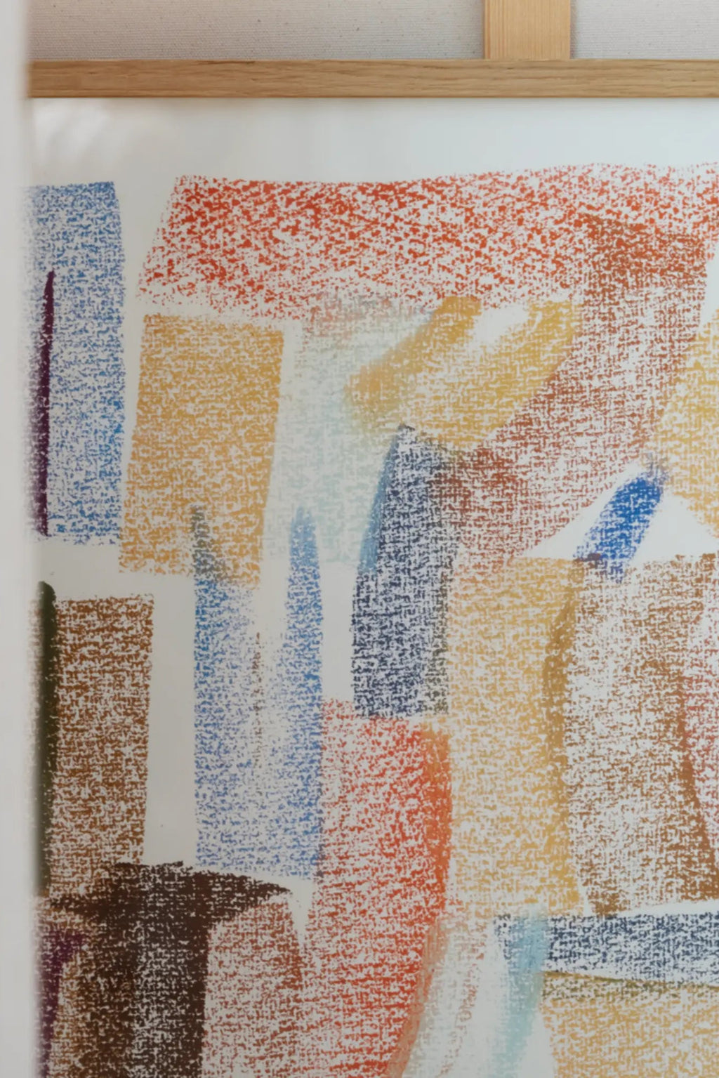 The Poster Club Sunset, a vibrant abstract art print featuring a painterly composition of textured blocks in warm rust orange, golden yellow, and deep brown, accented by cool blues and hints of purple, rendered with a distinctive crayon-like texture. Framed in a light natural oak frame, this modern wall art is perfect for adding a touch of contemporary color to a living room, bedroom, or gallery wall.