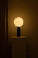 Table lamp with a round glass shade emitting warm light in a dark setting