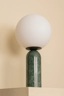 Lamp with a green base and white spherical shade on a beige background