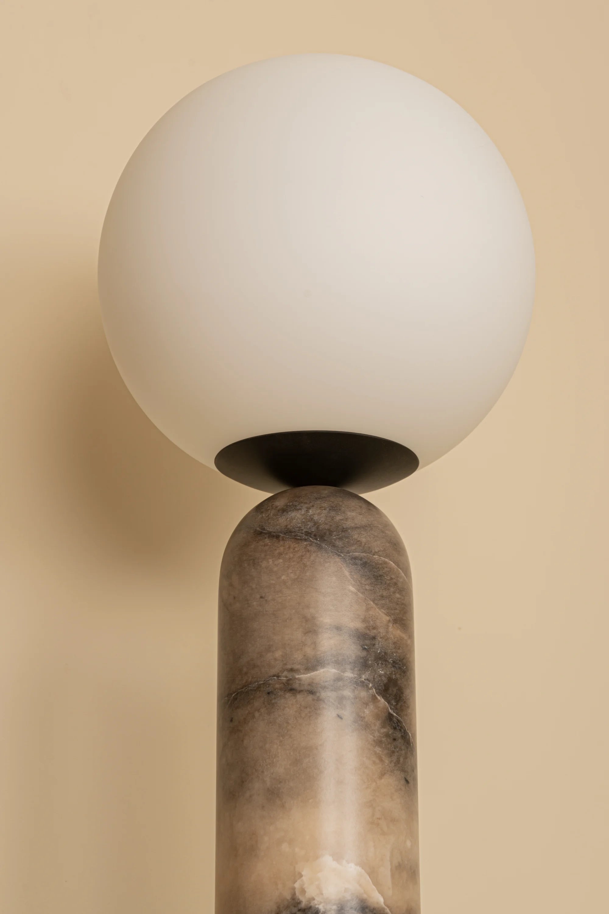 Spherical light fixture on a marble base against a beige background