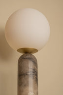 Lamp with a spherical glass shade on a marble base against a beige background