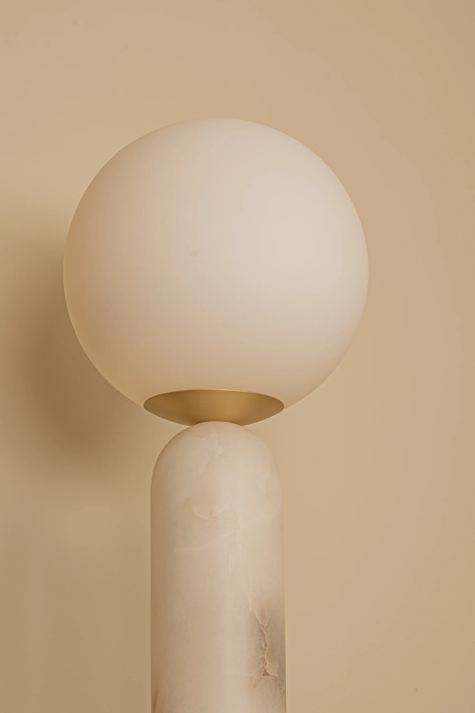 Modern wall lamp with spherical shade on a beige background