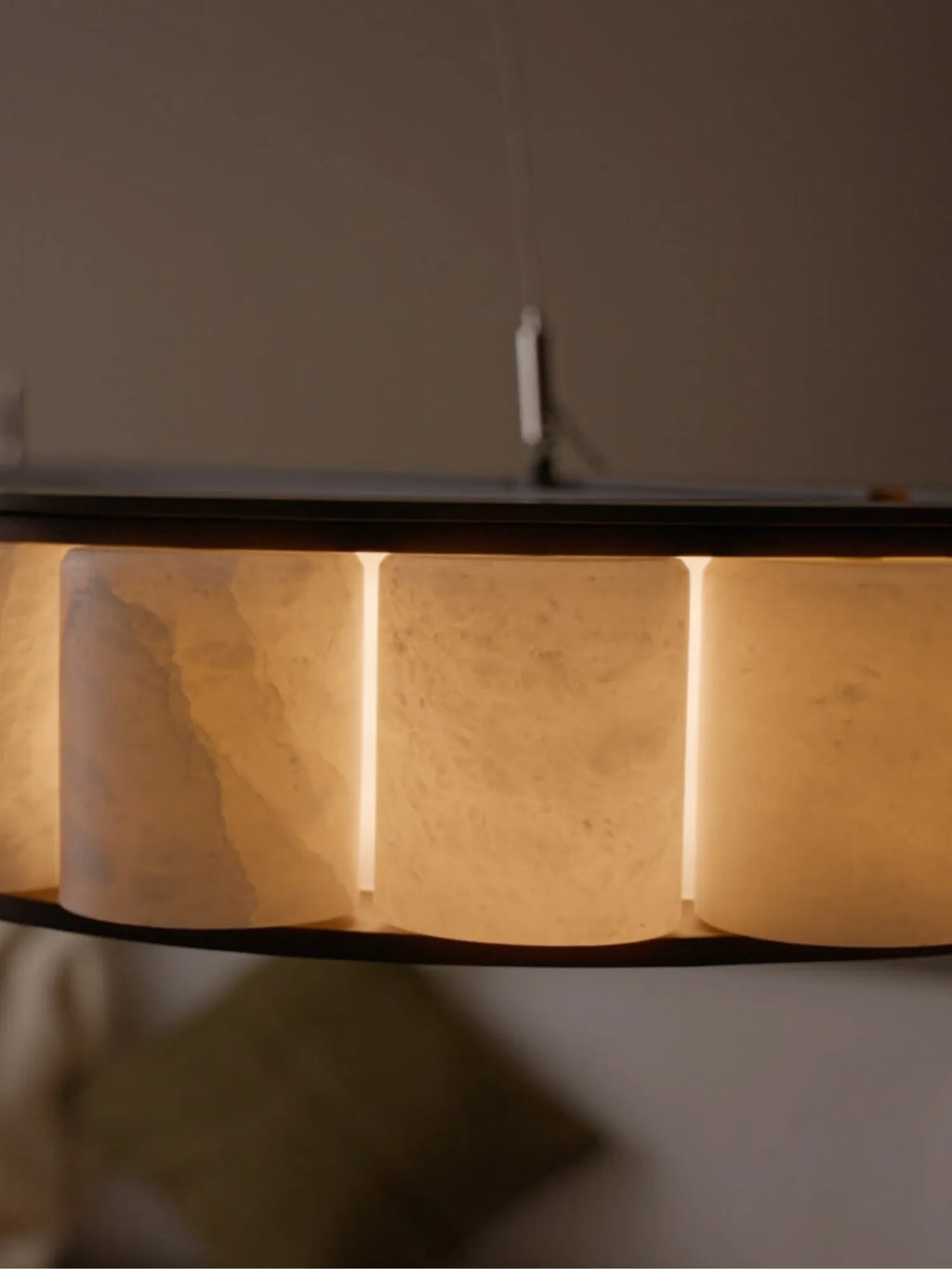 CTO Lighting Avalon Oval Pendant Light, a luxurious contemporary ceiling fixture featuring multiple translucent natural alabaster segments that emit a warm, diffused glow, elegantly framed by a sleek dark bronze metal band.