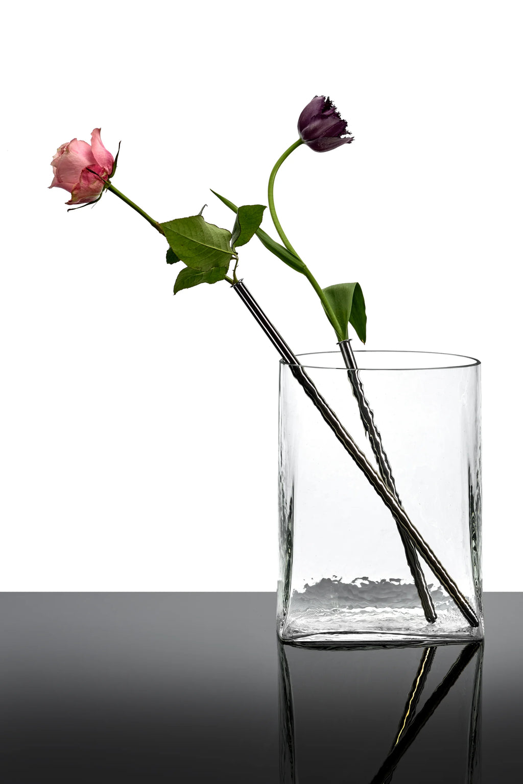Serax Josephine Vase with Glass Tube 03, a clear, textured glass cylinder vase with a wide opening, holding two flowers in individual slender metal tubes. This elegant decorative vase is perfect for displaying single stems or small bouquets in modern home decor settings.