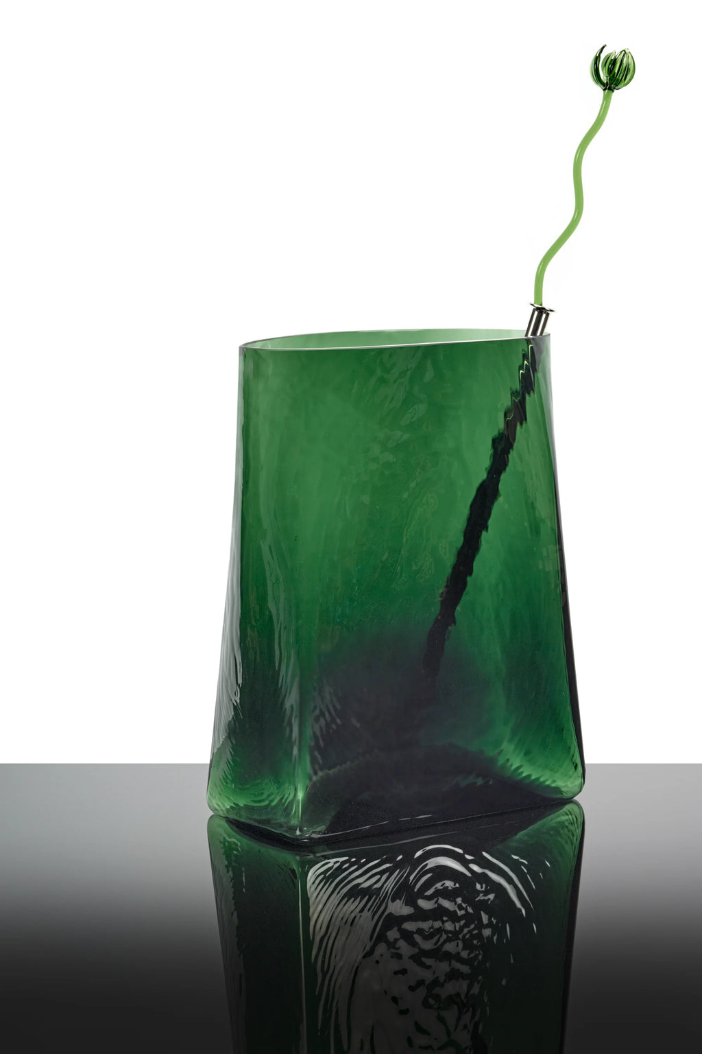 Serax Josephine Vase with Glass Tube 03, a contemporary dark emerald green glass vase with an organic, uneven texture and a narrow, flaring top. It includes a slim, wavy light green glass tube with a bulbous end designed to hold a single bloom. This unique decorative piece is perfect for modern home decor enthusiasts seeking a stylish and artistic floral display.