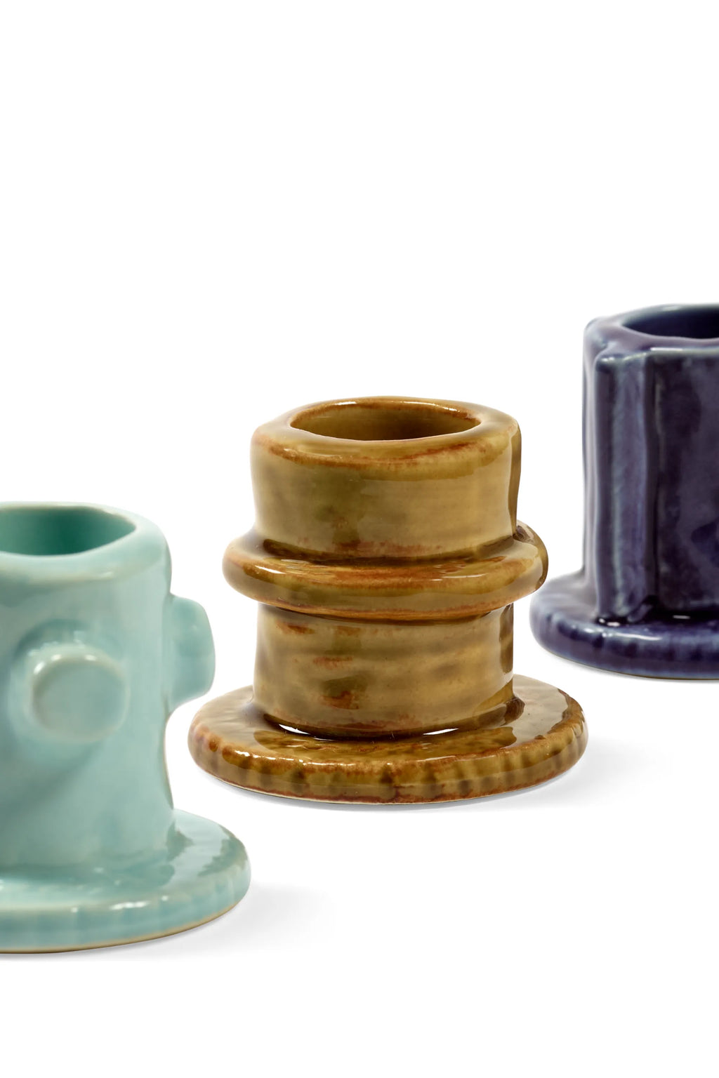 Serax Glazed Molly Candle Holder 01 - Set of 3, featuring three unique ceramic candle holders in varying heights and colors: a light teal with side protrusions, a central olive green with tiered rings, and a dark indigo blue with vertical ridges, all with a glossy finish. These stylish and decorative candle holders are perfect for adding a touch of modern elegance to any home decor.