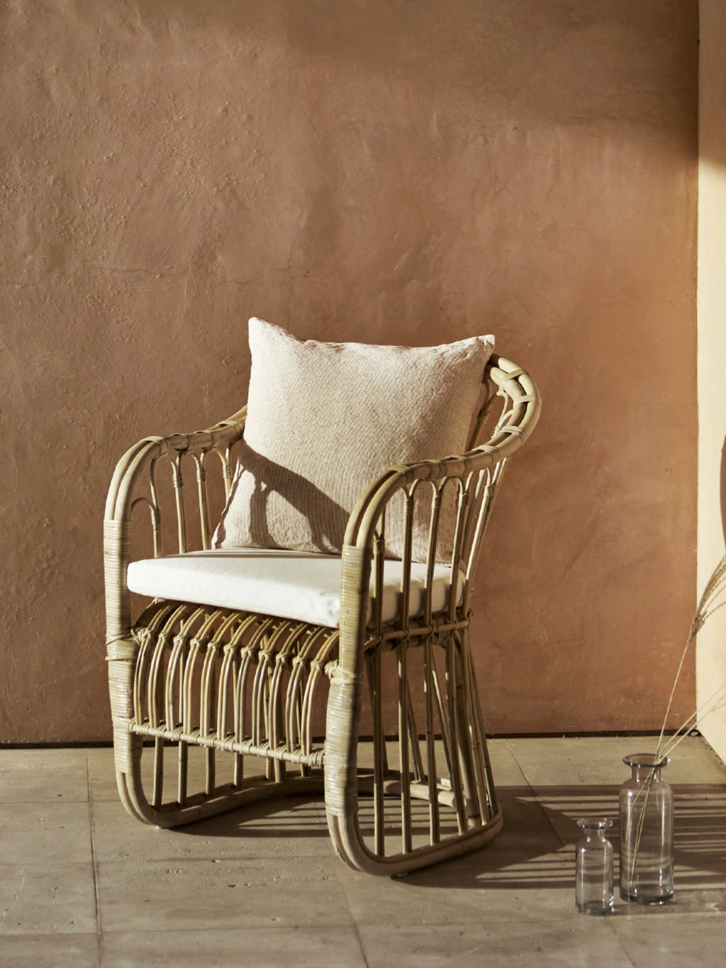 Tine K Rattan Dining Chair - Set of 2, a light natural rattan armchair featuring a beautifully woven open design, gently curved backrest, and comfortable armrests, complete with a plush cream fabric seat cushion and matching back pillow. This organic modern rattan chair set is perfect for creating a relaxed boho dining room, coastal living room accent, or inviting covered patio seating.