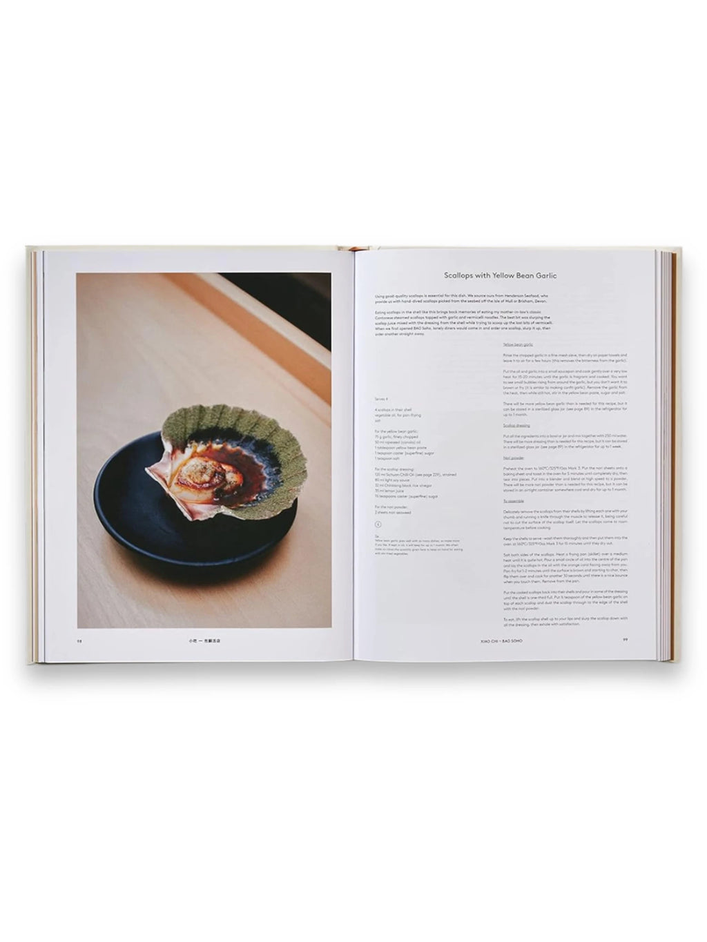 Book Bao, an open cookbook featuring a vibrant full-page image of a "Scallops with Yellow Bean Garlic" dish served in a natural scallop shell on a sleek black plate. This premium culinary book is perfect for home chefs and food enthusiasts eager to recreate authentic Asian recipes and explore gourmet cooking techniques.