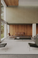 Modern living room with minimal furniture and large windows.