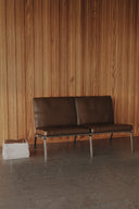 Brown leather sofa against a wooden paneled wall.