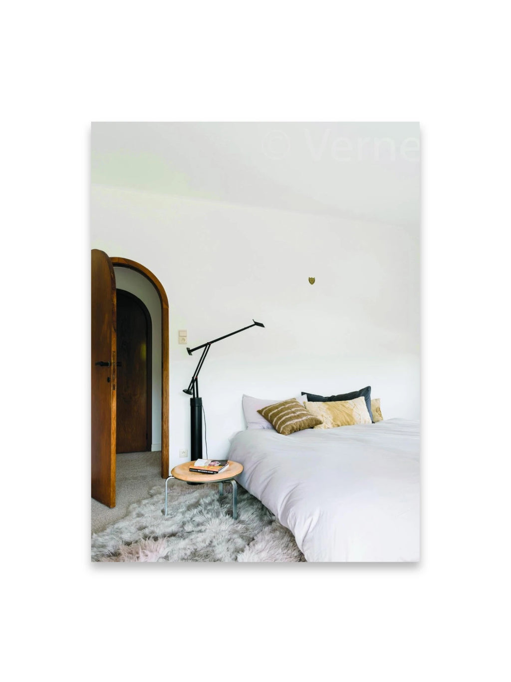 Book Bea Mombaers – items & interiors, featuring a cozy bedroom scene with a white duvet, golden accent pillows, a modern black floor lamp, and a light wood side table atop a plush gray shag rug. This inspiring interior design book is perfect for home decor enthusiasts seeking stylish ideas and artistic inspiration.