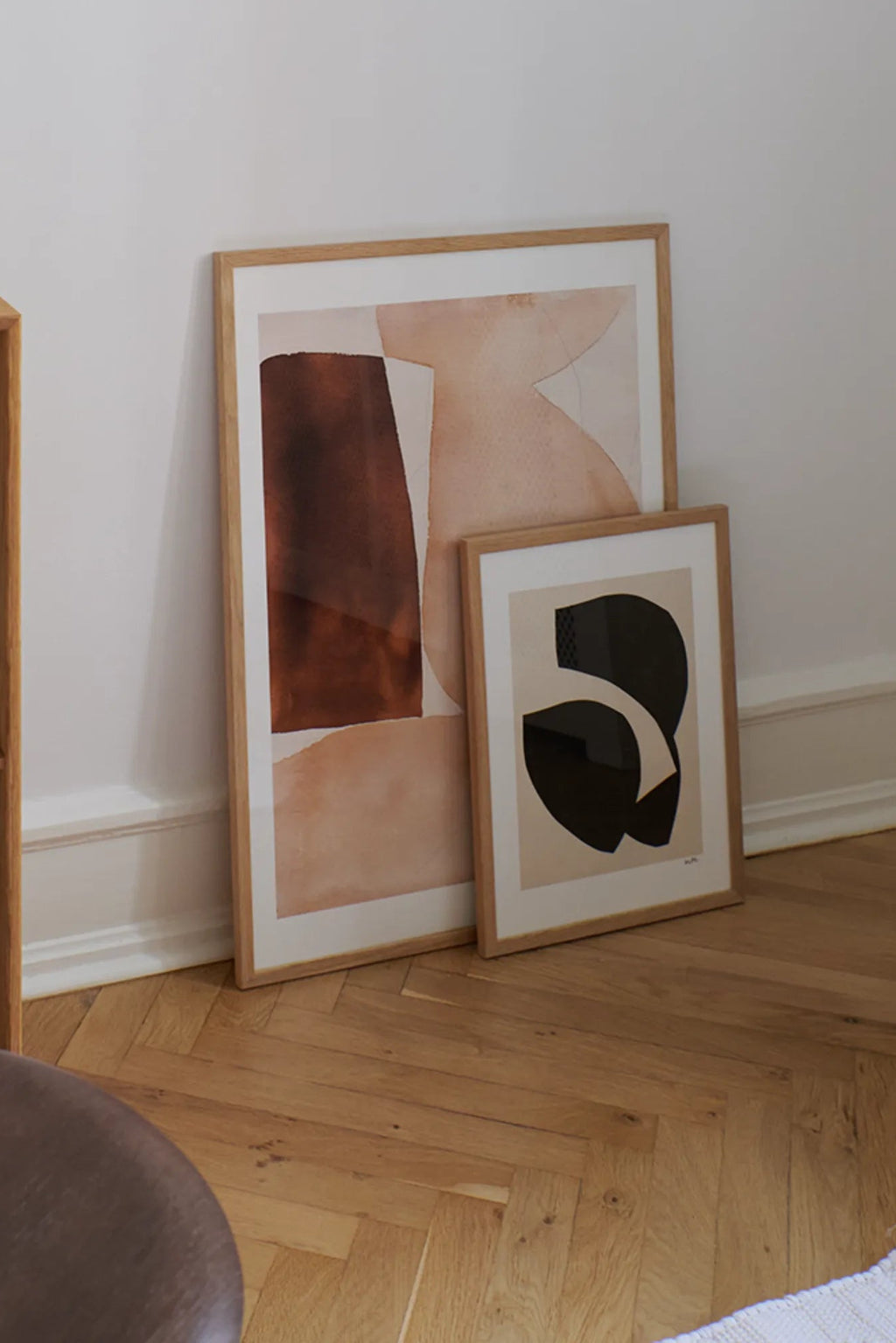 The Poster Club Bloom, a large abstract art print featuring organic shapes in warm terracotta, soft beige, and deep brown watercolor tones, framed in light natural oak.