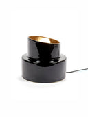 Black cylindrical lamp with gold interior on a white background