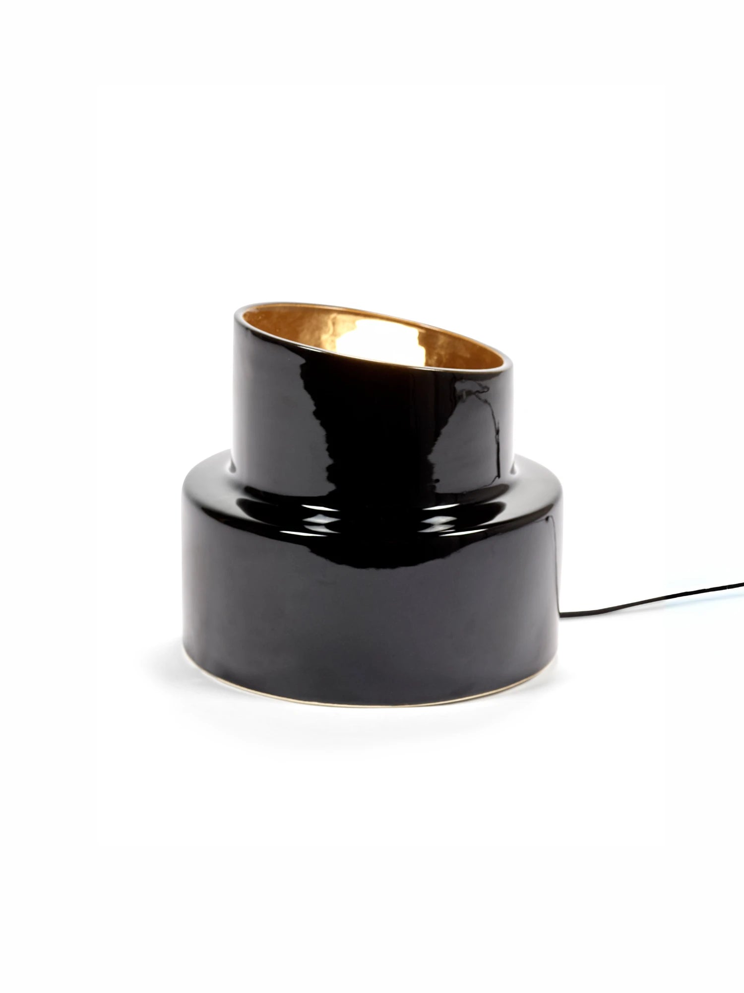 Black cylindrical lamp with gold interior on a white background