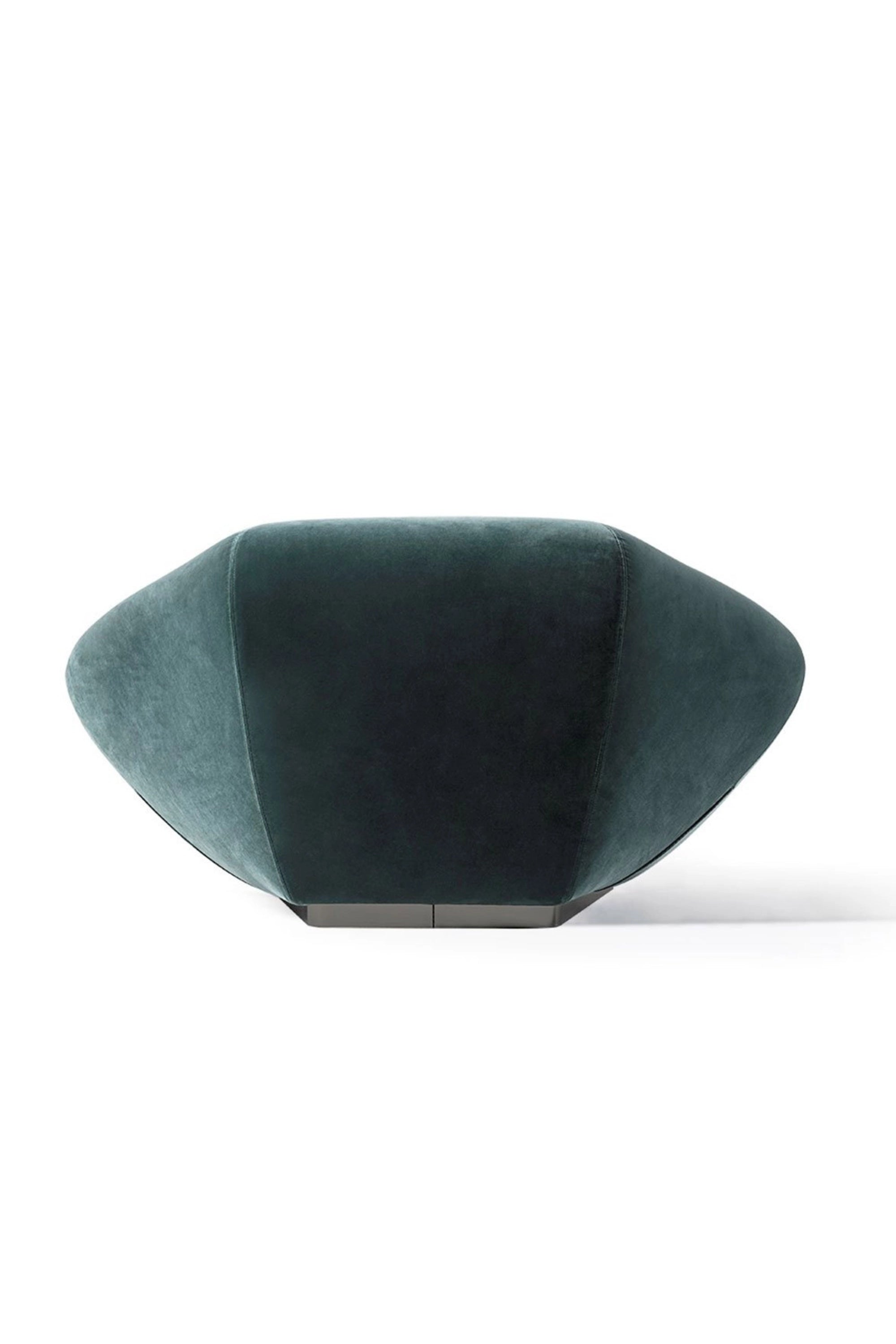 Hessentia Bloom Armchair, a contemporary lounge chair featuring a unique sculptural design upholstered in plush deep teal velvet fabric with a soft, inviting texture. Its organic, faceted shape and low profile are supported by a sleek, dark matte metal base, creating a luxurious statement piece. This designer armchair is perfect for modern living rooms, sophisticated bedrooms, or any luxury interior seeking an artistic focal point.
