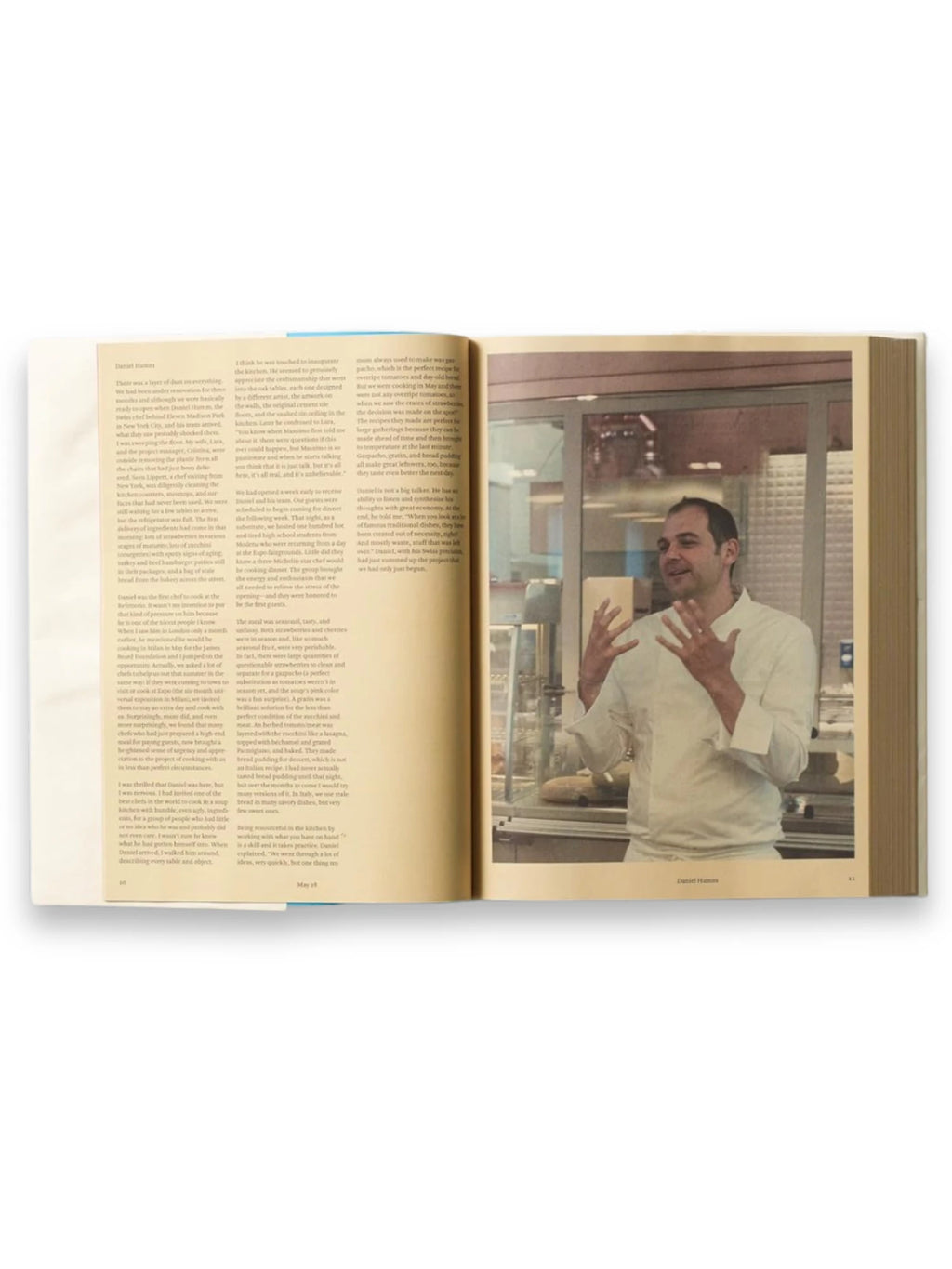 Book Bread is Gold: Extraordinary Meals With Ordinary Ingredients, an open hardcover cookbook showcasing an elegant page spread with a black-and-white photograph of chef Daniel Humm in a kitchen on the right, accompanied by text on the left. This essential culinary book is perfect for home cooks and aspiring chefs seeking creative, resourceful recipes.