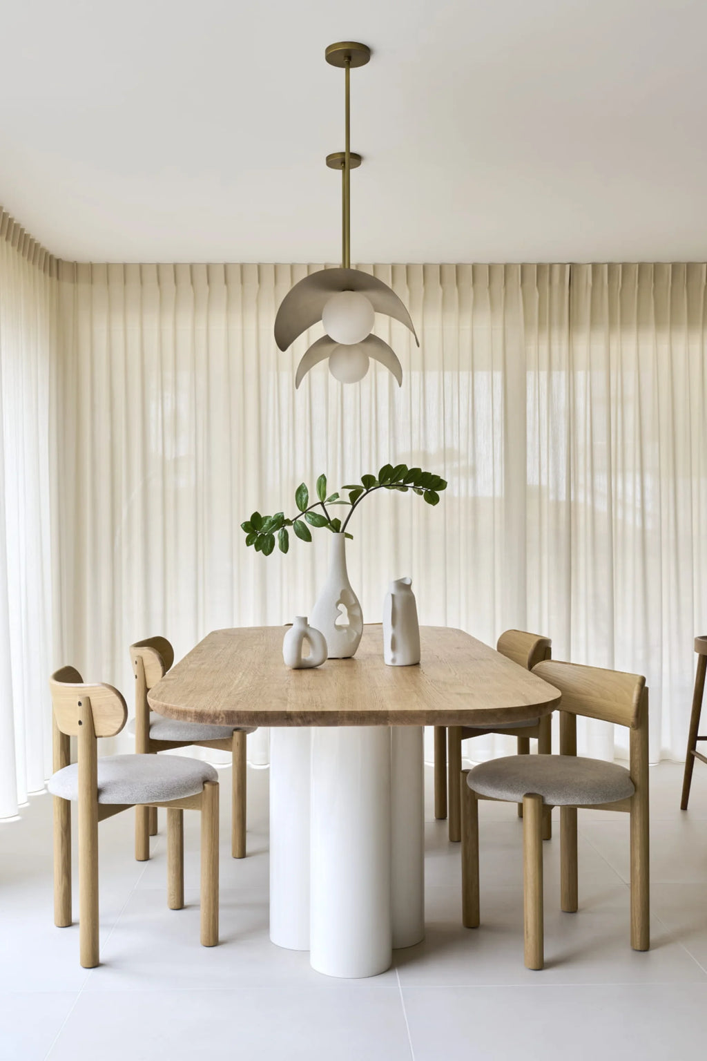 NG DESIGN Object 071 Dining Table, a premium light oak wood tabletop with rounded corners and a unique trio of white cylindrical bases, captured in a chic dining space with modern wood and upholstered chairs. Ideal for sophisticated interiors.