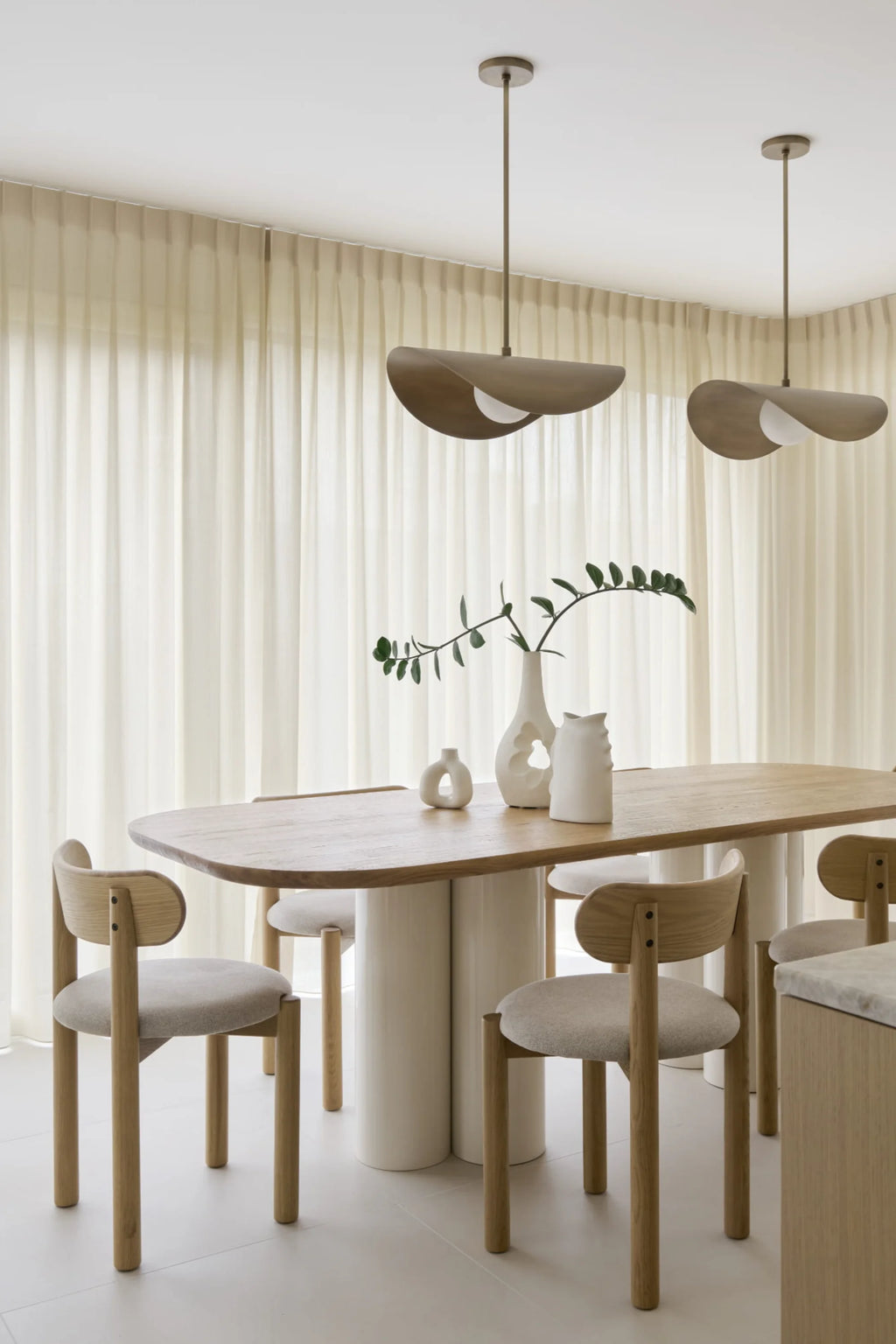 NG DESIGN Object 071 Dining Table, featuring a light wood oval top and white cylindrical bases. This luxury modern dining table is styled with chairs, vases, and green branches against a sheer curtain background. Perfect for contemporary dining spaces.