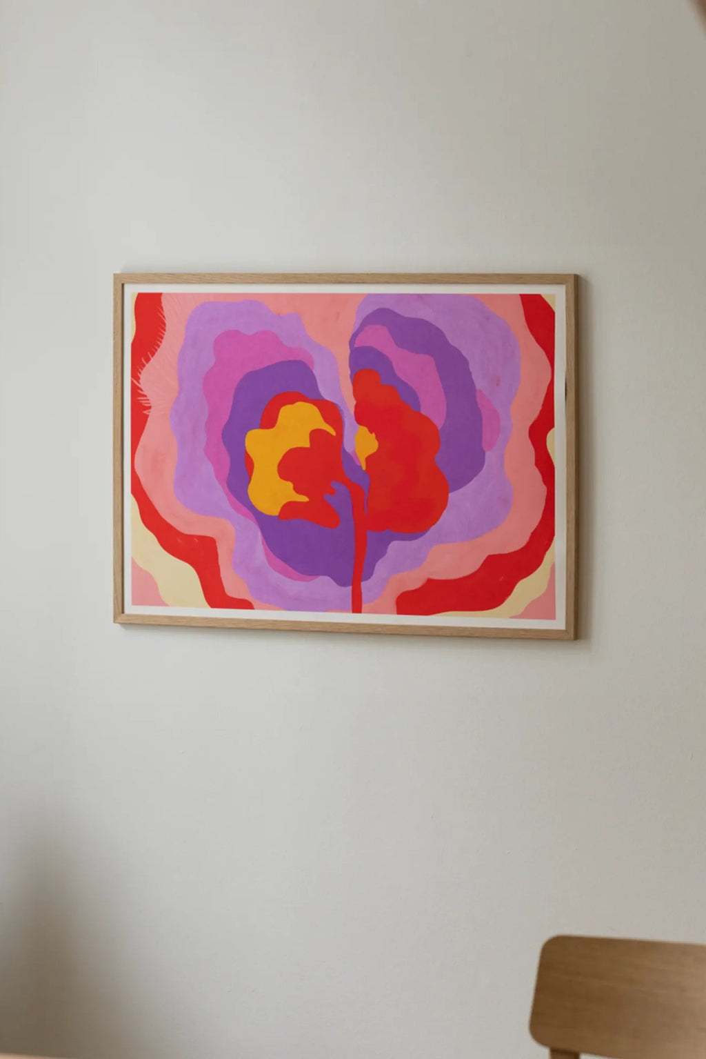 The Poster Club Aurora, a vibrant abstract art print featuring organic wavy shapes in bold red, orange, pink, and purple tones, framed in natural oak. Perfect for contemporary gallery walls or adding a colorful statement to modern living rooms and bedrooms.