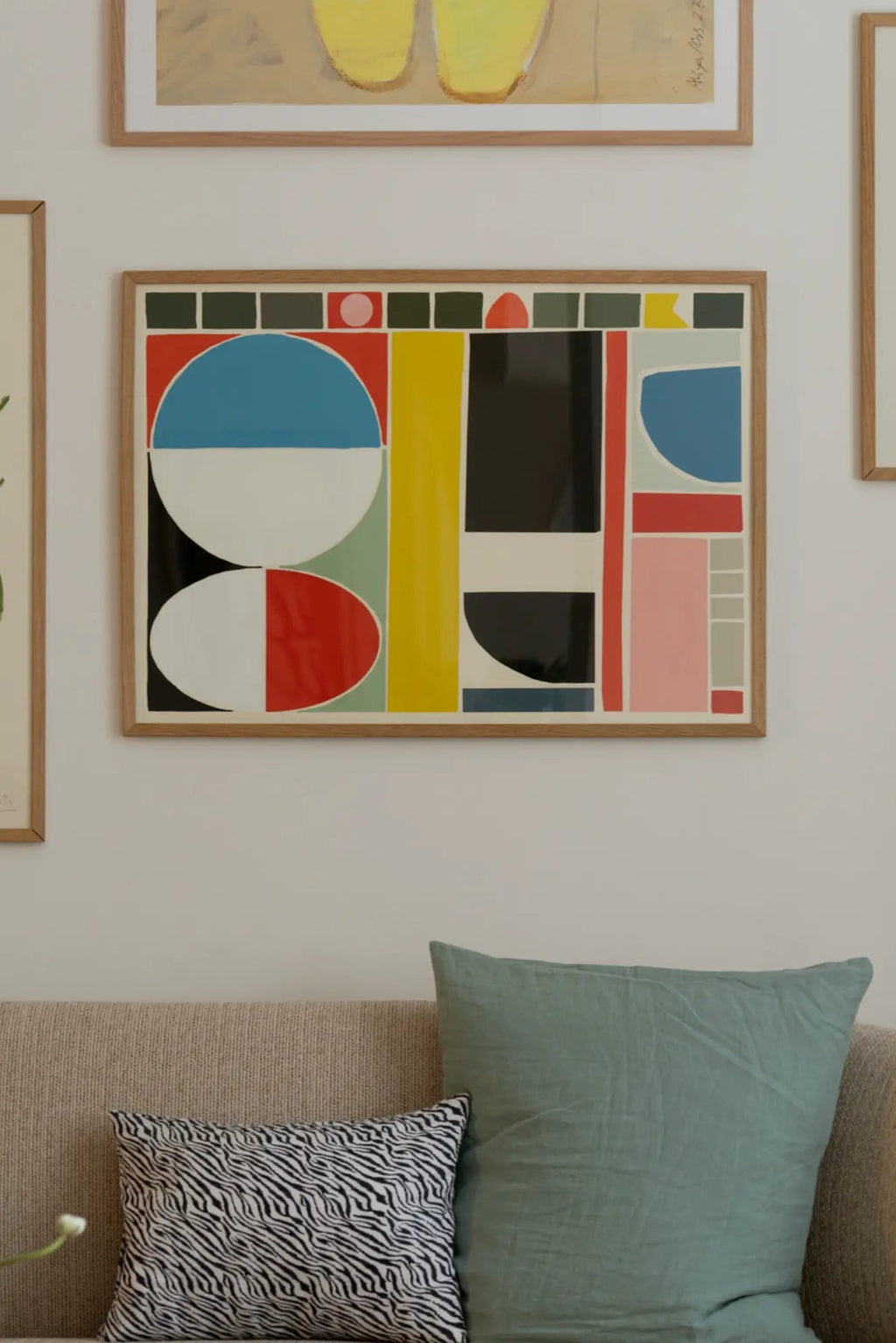 The Poster Club Palette, a vibrant abstract art print featuring a bold composition of geometric shapes like circles, ovals, and rectangles in striking primary colors of red, blue, and yellow, contrasted with black, white, pink, and green elements. Framed in a light natural oak frame, this contemporary wall art piece is perfect for modern gallery walls, living rooms, or creative home office spaces.
