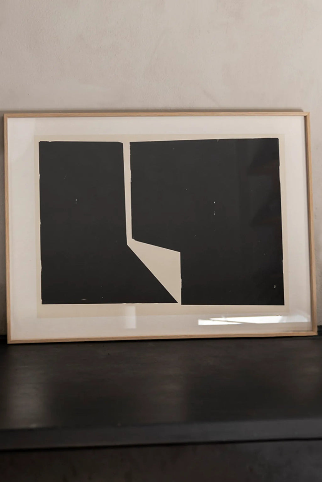 The Poster Club Facesing, a striking modern minimalist abstract art print showcasing bold black geometric shapes against an off-white background, creating a graphic and contemporary design. This framed art print is presented in a light natural oak frame with a crisp white mat. It's an ideal piece of Scandinavian wall art for minimalist living rooms, modern bedrooms, or sophisticated gallery wall styling.