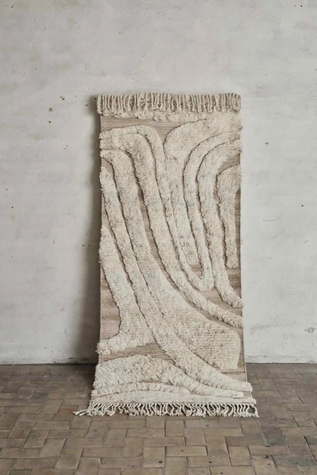 Cappelen Dimyr Colonnade No.01 Rug, a luxurious hand-knotted wool rug featuring a high-pile shaggy texture in natural undyed cream and ivory tones, contrasted with a flat-woven natural beige base. Its organic wavy pattern creates a striking abstract design, finished with decorative fringe at both ends. Ideal as a statement organic modern area rug for living rooms or a unique textured wall hanging for contemporary Scandinavian and minimalist spaces.