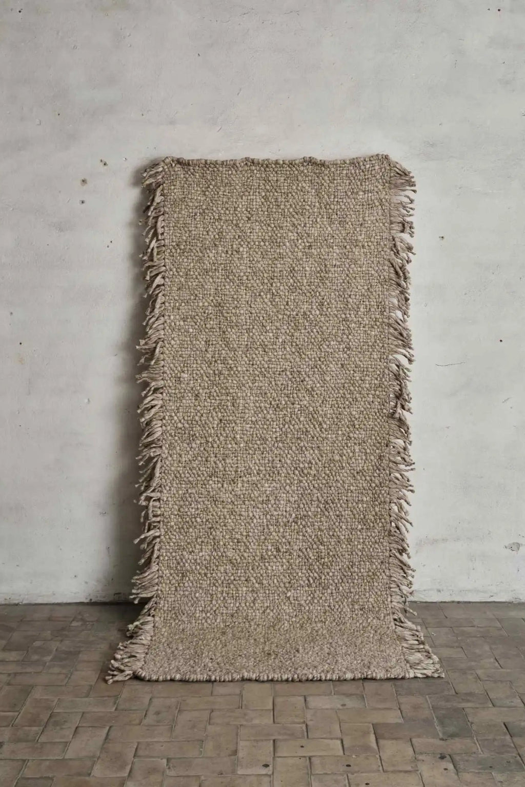 Cappelen Dimyr Colonnade No.03 Rug, a hand-knotted wool runner rug featuring a chunky textured weave in natural beige and greige tones, with raw, shaggy fringed edges along the long sides. This organic modern rug is perfect for adding warmth and texture to Scandinavian hallways, rustic bedrooms, or minimalist living spaces.
