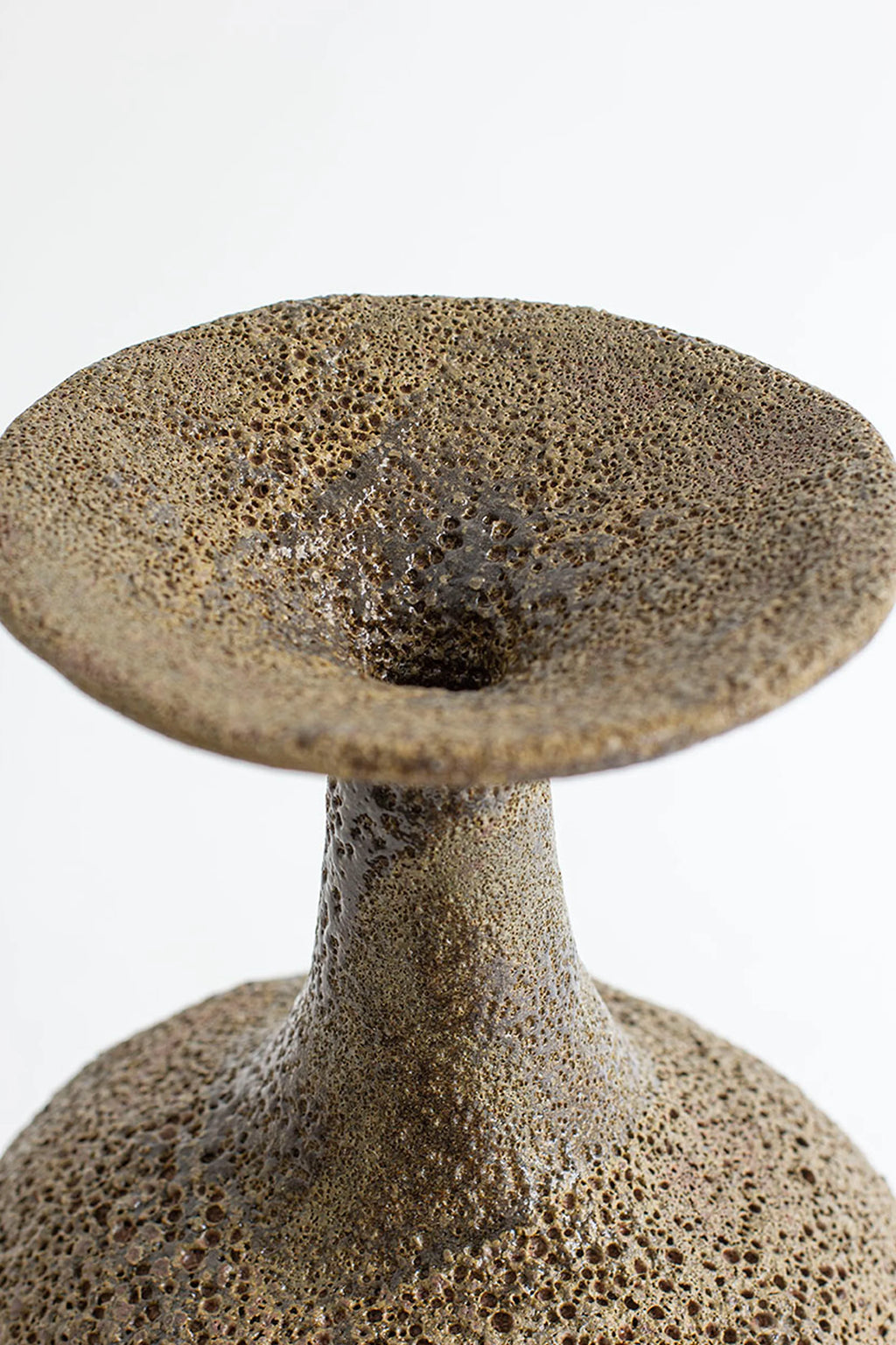 Canoa Lab Arq 002 Musgo Vase, a handcrafted ceramic vase in earthy moss brown tones featuring a deeply textured, porous volcanic finish and a distinctive flared rim atop an organic sculptural form. This artisanal stoneware vase is perfect for organic modern shelf styling, adding rustic charm to living room decor, or serving as a unique statement piece for wabi-sabi interiors.