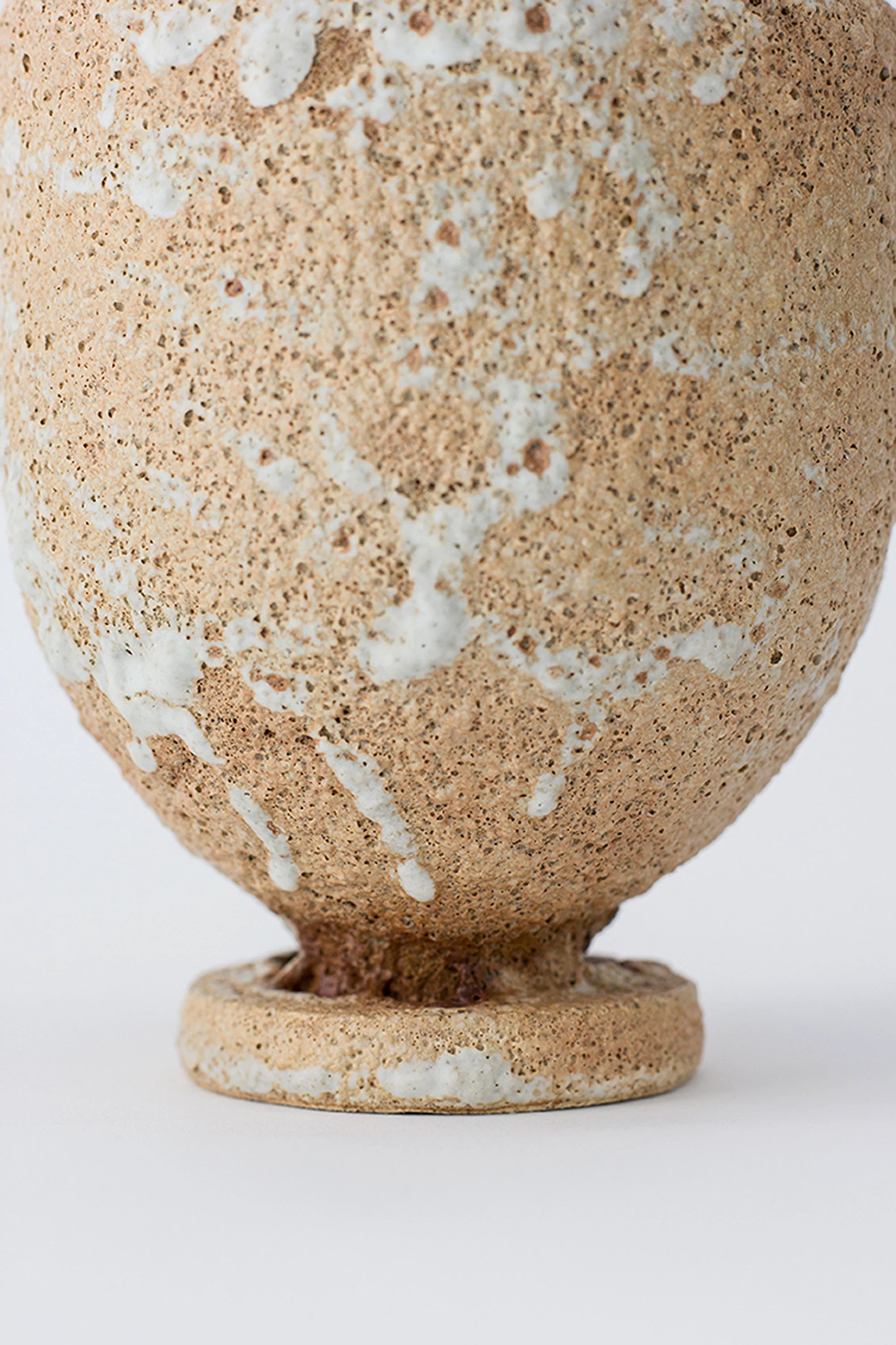 Textured ceramic vase with beige and white speckled pattern on a white background