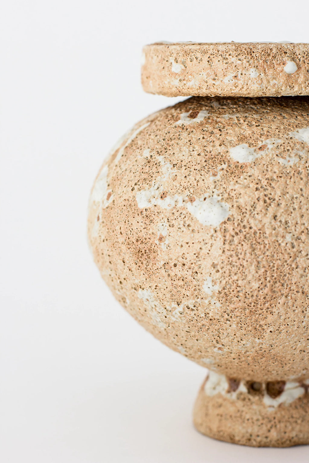 Canoa Lab Arq 004 Vase, a close-up side view of the modern, rounded ceramic vase, highlighting its textured, earthy beige and white porous finish with unique patterns, displayed on a clean white background.