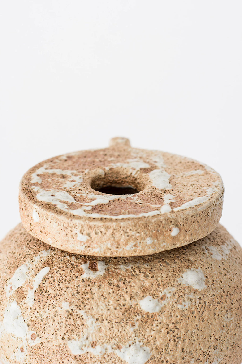 Canoa Lab Arq 004 Vase, a close-up top view of the modern ceramic vase's lid, showcasing its textured, earthy beige and white porous finish and circular design, displayed on a clean white background.