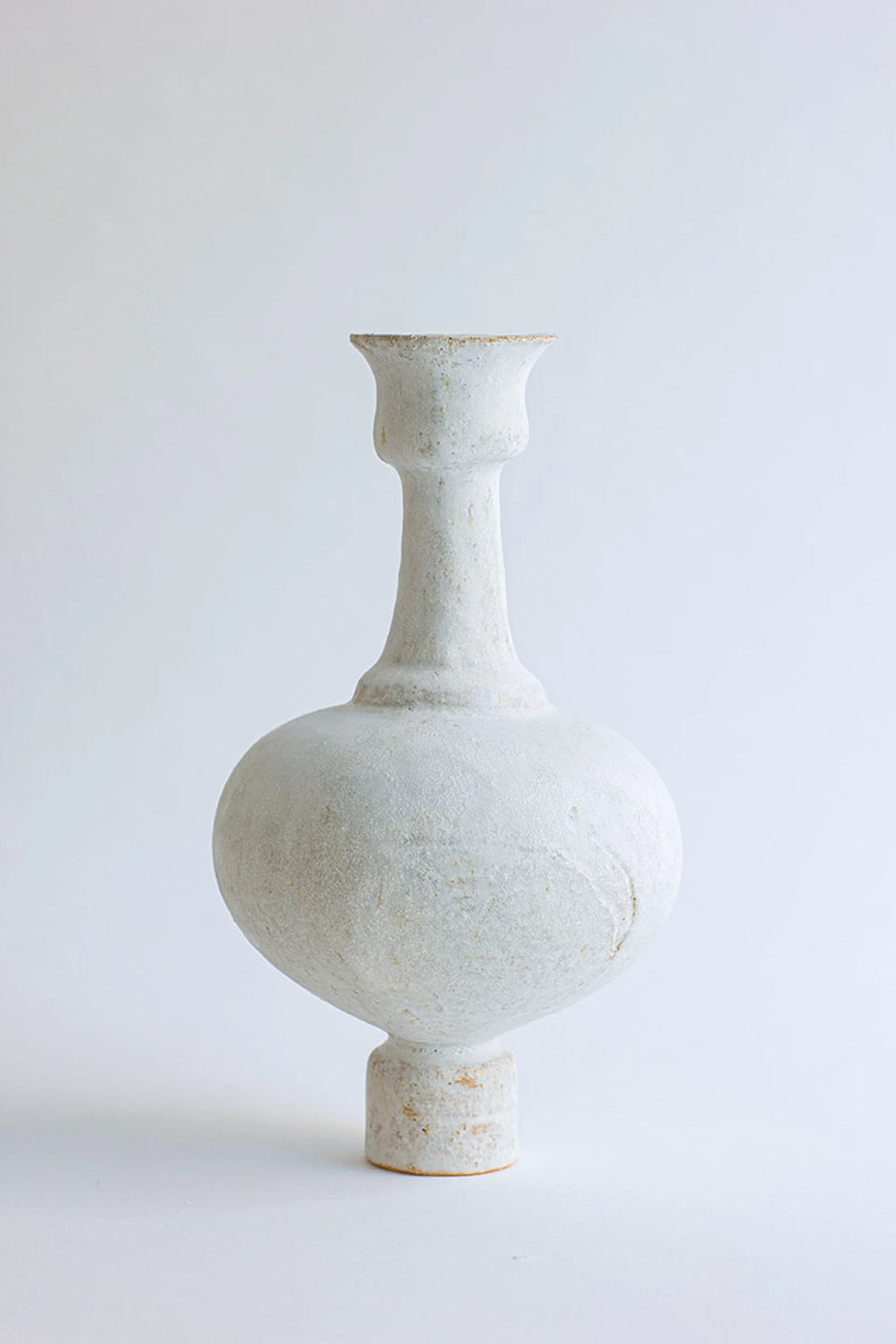 Canoa Lab Arq 005 Blanco Hueso Vase, a handcrafted bone white ceramic vase with a unique sculptural shape, featuring a bulbous body, slender neck, flared rim, and a textured, porous finish. This organic modern stoneware vase in a natural off-white tone brings wabi-sabi elegance to minimalist living rooms or contemporary shelf styling.