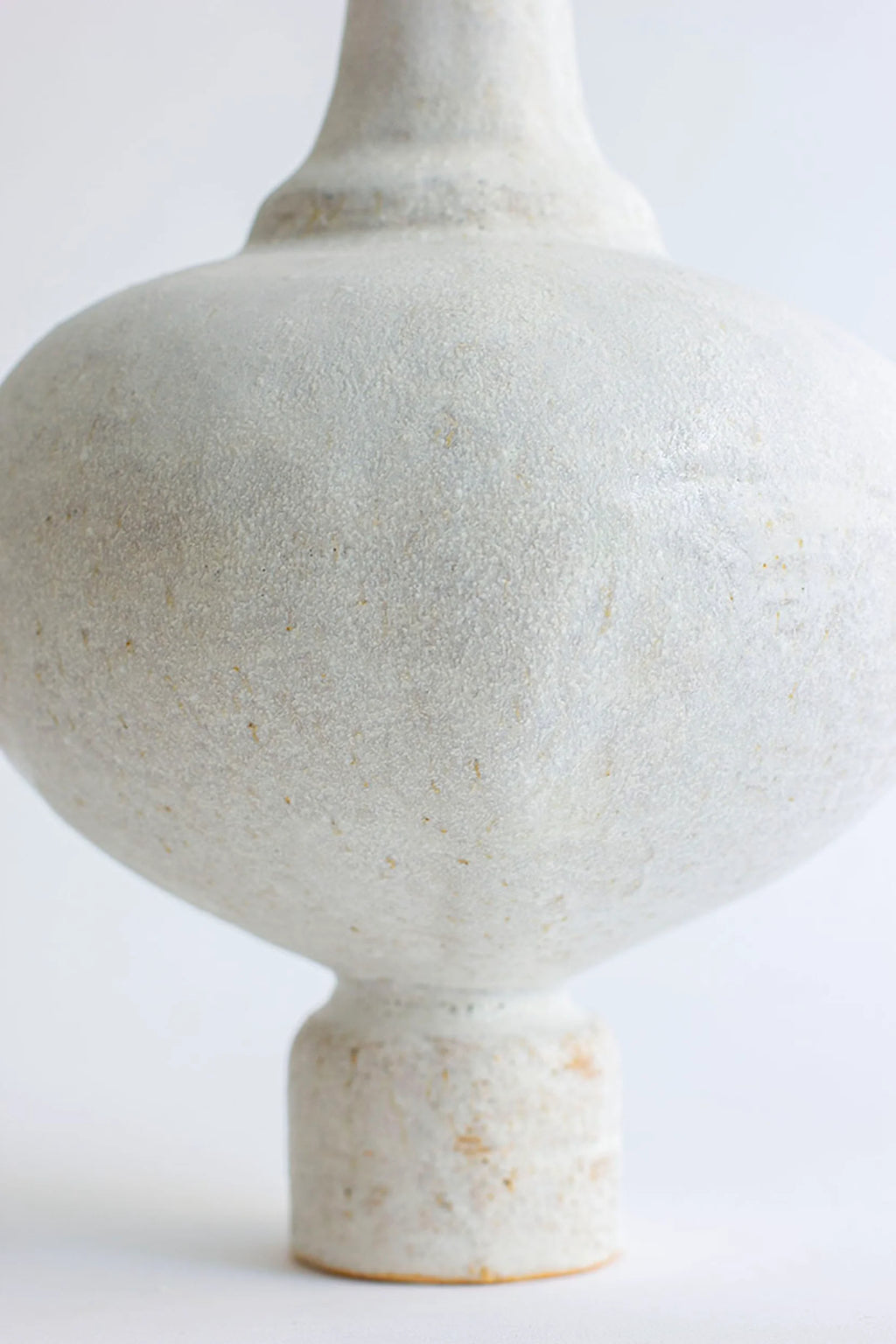 Canoa Lab Arq 005 Blanco Hueso Vase, a sculptural organic modern ceramic vase with a distinctive bulbous silhouette and narrow neck, crafted from handcrafted stoneware in a bone white finish. It features a unique, highly textured, porous, and sandy matte surface, ideal for wabi-sabi or minimalist shelf styling in contemporary living rooms.