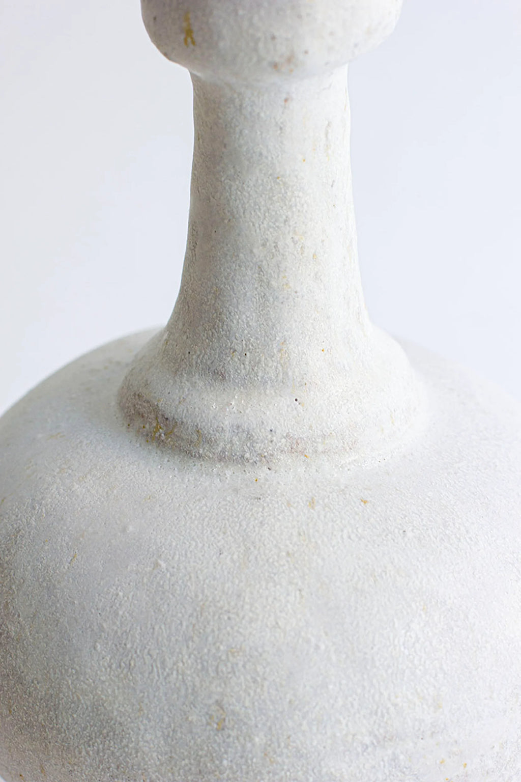 Canoa Lab Arq 005 Blanco Hueso Vase, a handcrafted ceramic vase in a warm bone white, featuring a distinctive textured, porous finish with subtle natural inclusions. This artisanal stoneware piece boasts an organic shape with a rounded body and a gently tapered neck. Ideal for organic modern shelf styling, wabi-sabi interiors, or as a minimalist living room accent.
