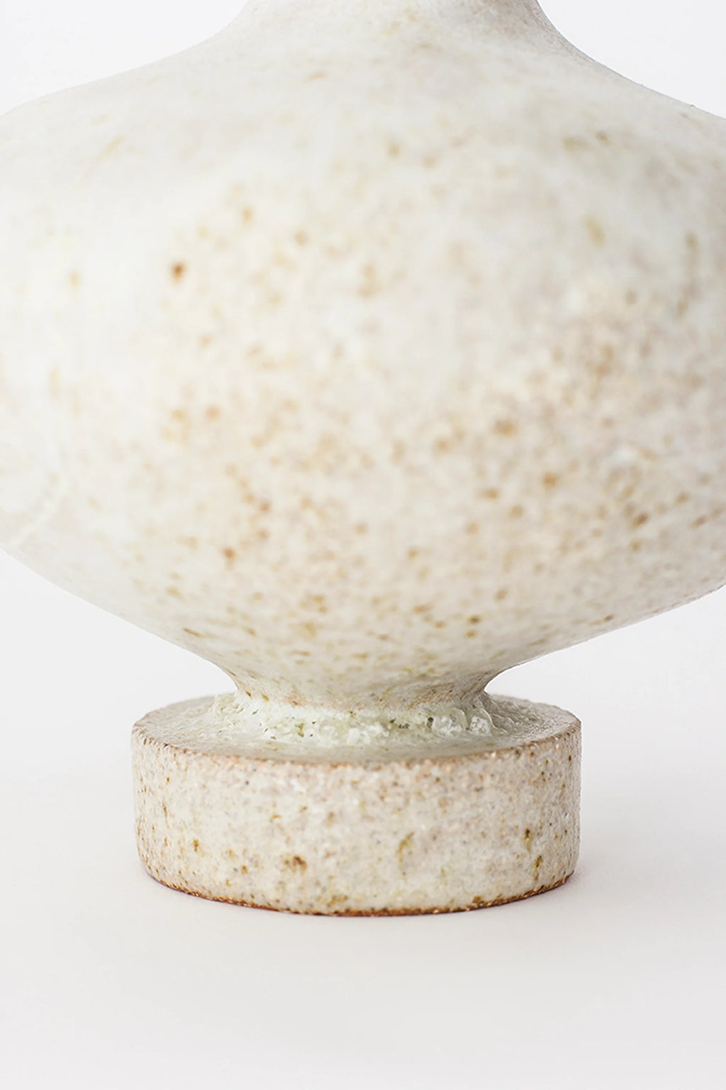 Canoa Lab Arq 006 Vase, a close-up of the sturdy, round base and lower body of the elegant ceramic vase. The speckled off-white finish with subtle earthy tones emphasizes the handcrafted texture and stable, modern design. Displayed on a clean white background.