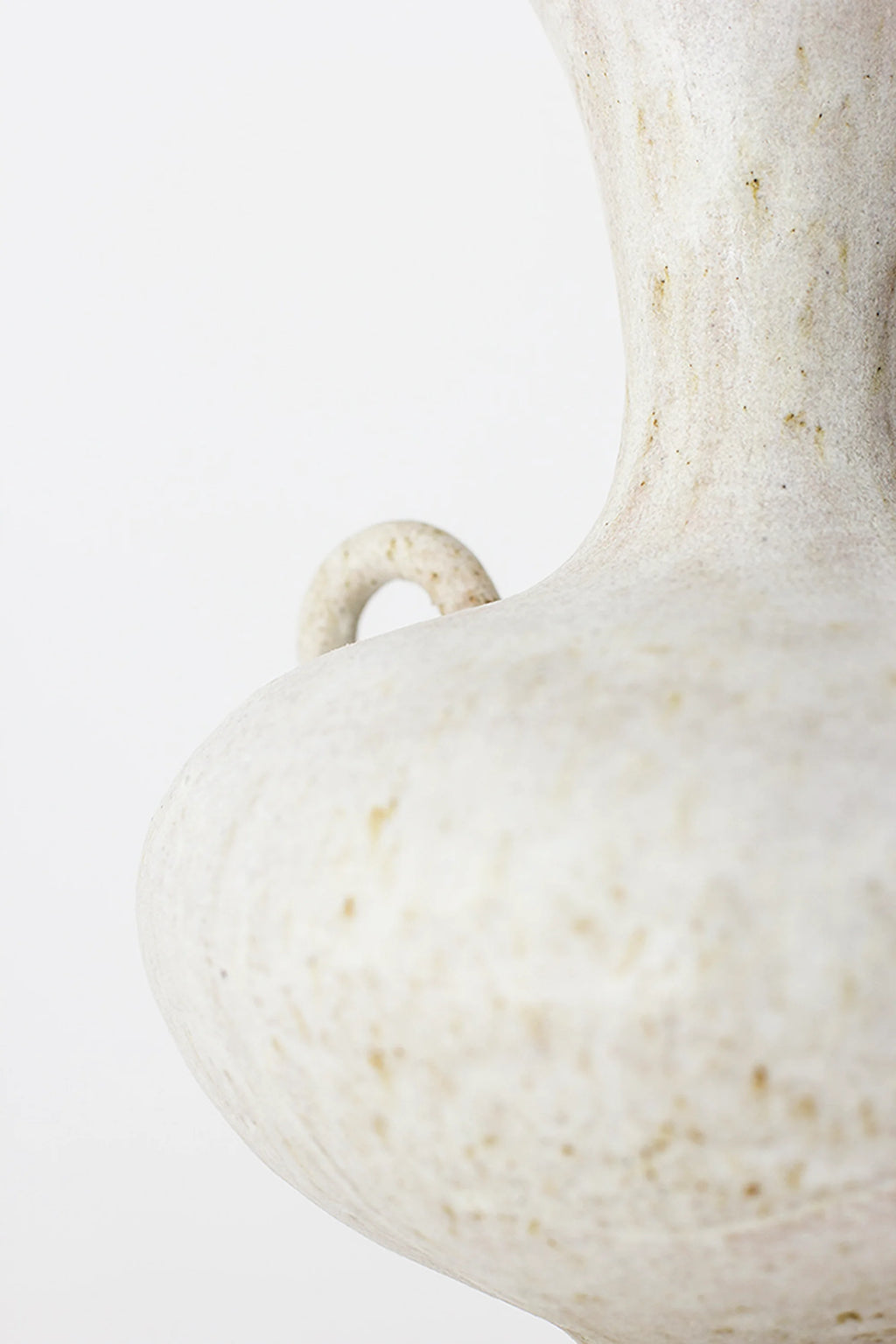 Canoa Lab Arq 006 Vase, a close-up side view of the bulbous body and small, decorative handle of the elegant ceramic vase. The speckled off-white finish with subtle earthy tones showcases the artisanal texture and unique, modern design. Displayed on a clean white background.