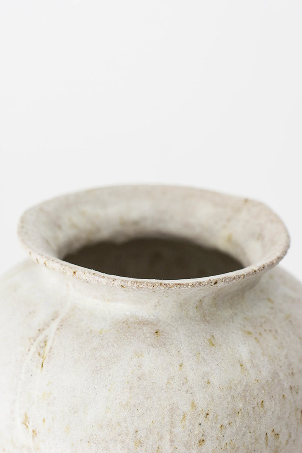 Canoa Lab Arq 007 Vase, a close-up of the top opening of the modern ceramic vase, revealing its speckled off-white texture and subtle earthy flecks. The rim is slightly flared, highlighting the artisanal craftsmanship and unique, organic design. Displayed on a white background.