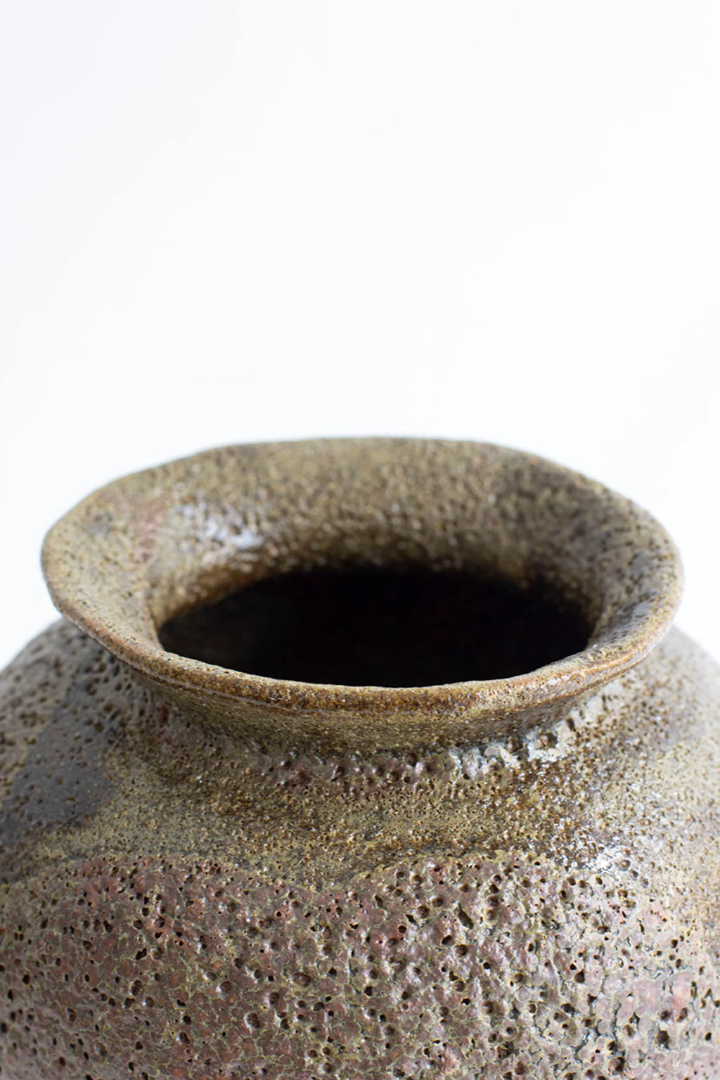 Canoa Lab Arq 007 Musgo Vase, a rustic, handcrafted ceramic vase with a textured, porous surface in earthy brown and green tones, showcasing its unique rim and opening, on a white background.
