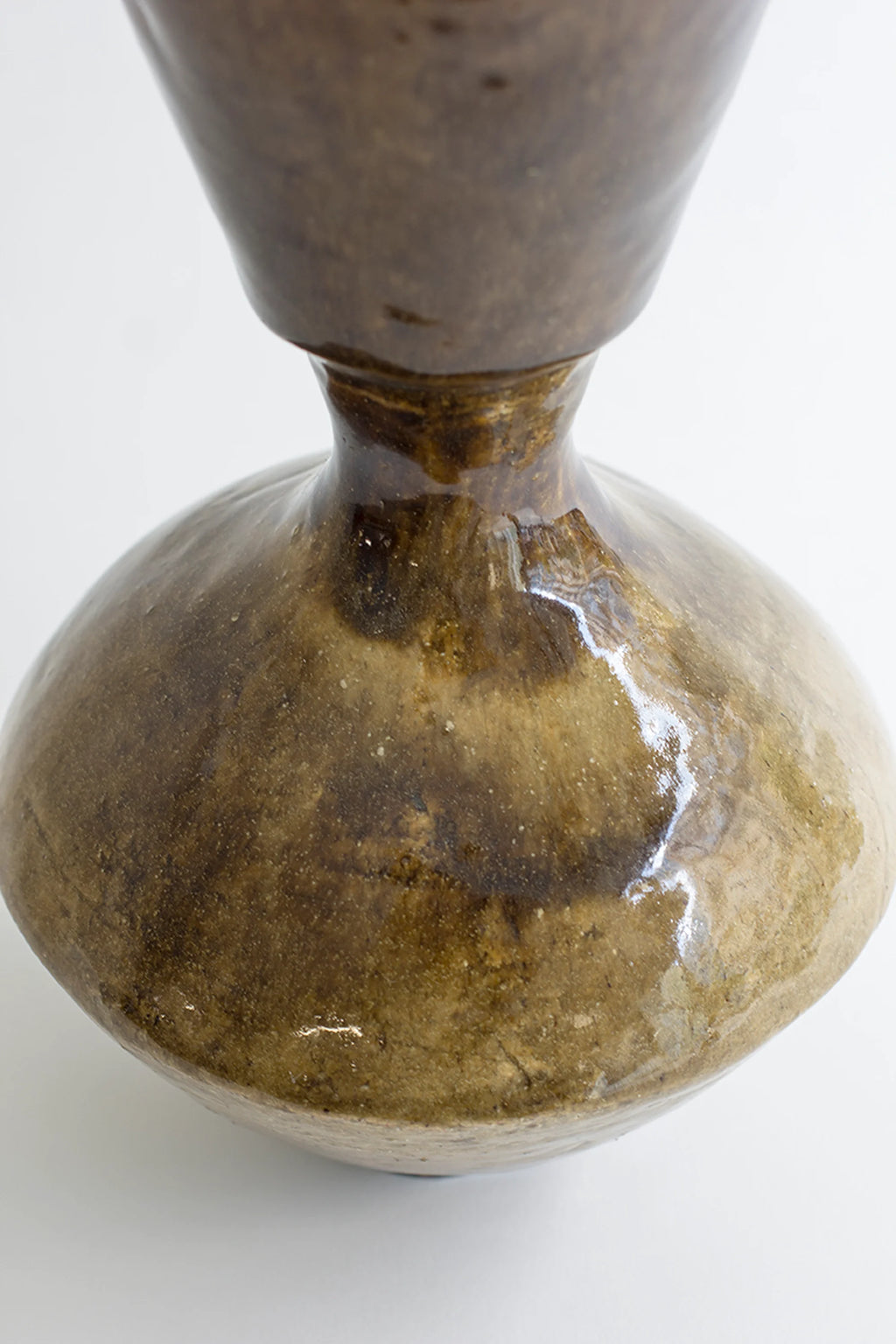 Canoa Lab Arq 008 Vase, a handcrafted stoneware vase with a unique organic, bulbous shape and a tapering neck, featuring an earthy olive green and brown reactive glaze with speckled texture and glossy highlights. This artisanal ceramic piece is perfect for wabi-sabi or organic modern shelf styling in living rooms or entryways.