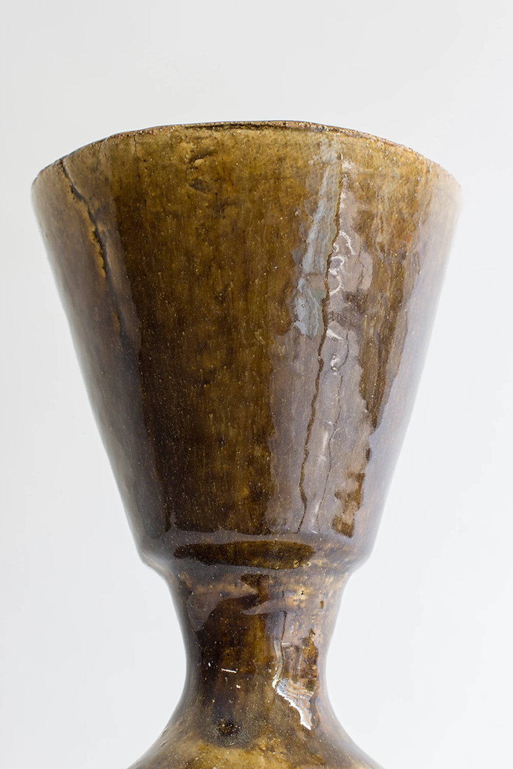 Canoa Lab Arq 008 Vase, a handcrafted ceramic vase featuring a rich, dark brown and bronze reactive glaze that showcases an organic, textured surface and a tapered, fluted silhouette. This artisanal stoneware piece features varied earthy tones and a glossy finish, highlighting its rustic charm. Perfect for adding an organic modern accent to shelf styling, living room decor, or as a unique dining table centerpiece.