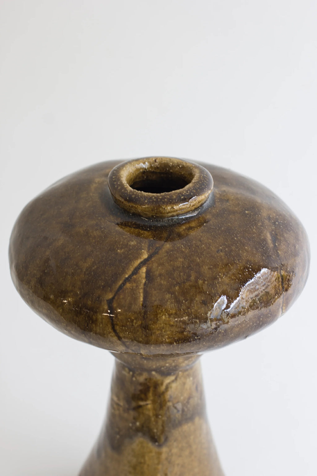 Canoa Lab Arq 009 Vase, highlighting the intricate details of its glossy dark brown glaze with visible crackle patterns, and a small, circular opening at its wide, flat top, on a white background.