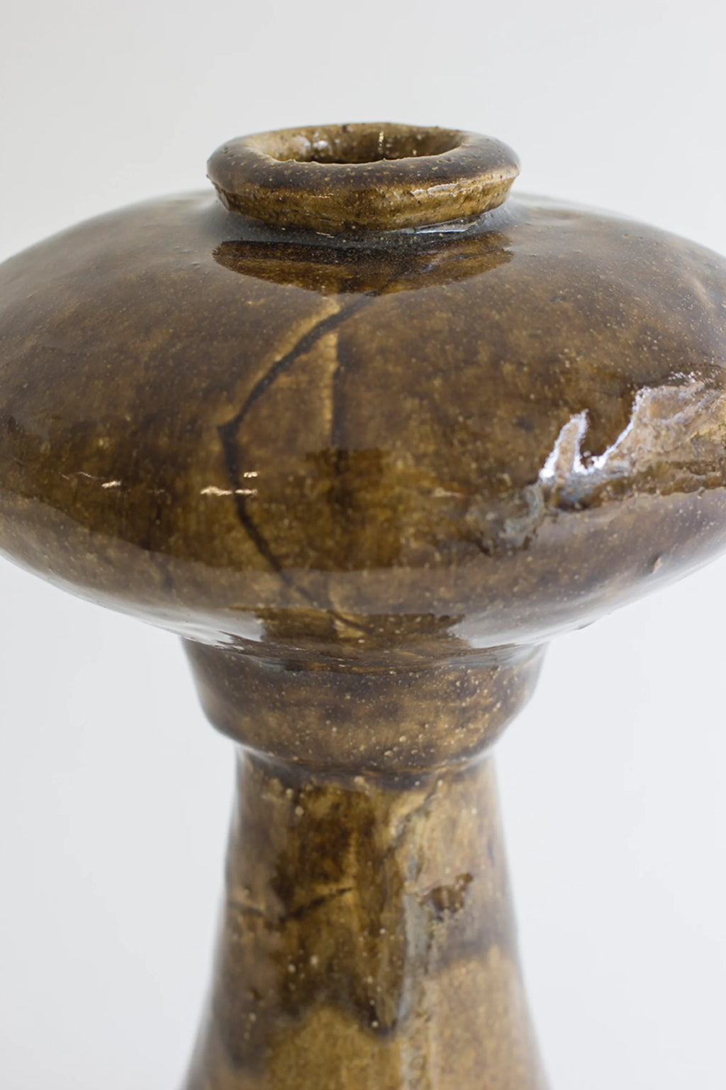 Canoa Lab Arq 009 Vase, a close-up view revealing the rich, glossy dark brown ceramic with subtle crackle textures, and the elegant, minimalist design of its wide top and small opening, on a white background.