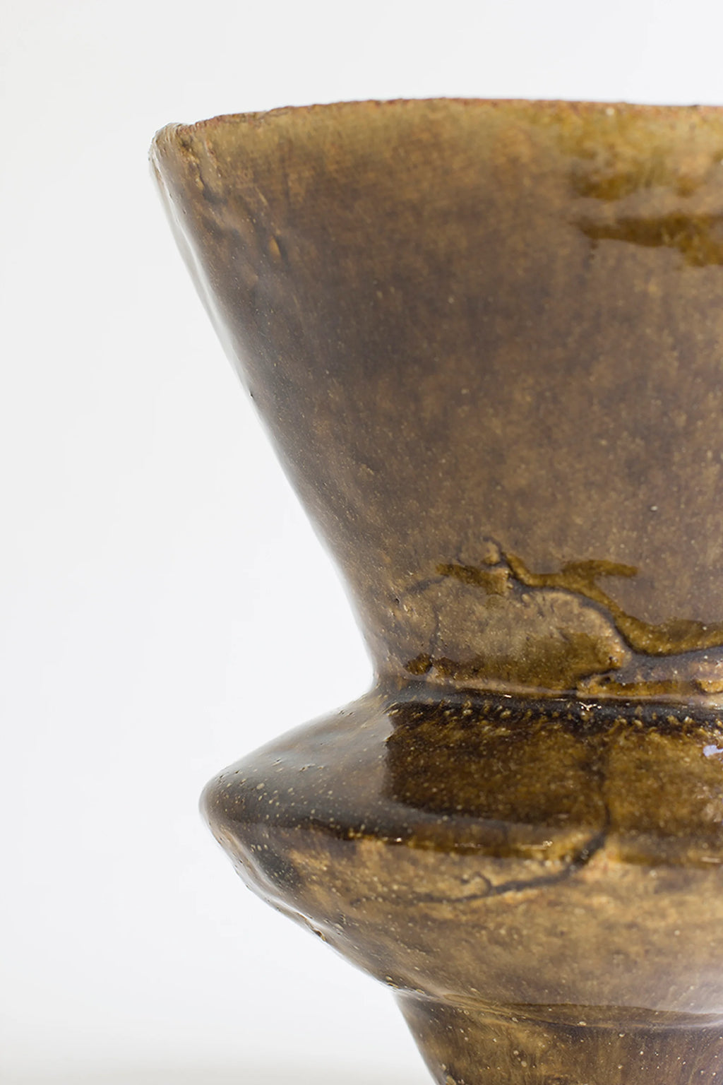 Canoa Lab Arq 010 Vase, a side view of the artisanal ceramic vase, showcasing its unique flared top and bulbous mid-section, with a glossy dark brown, textured glaze, on a white background.