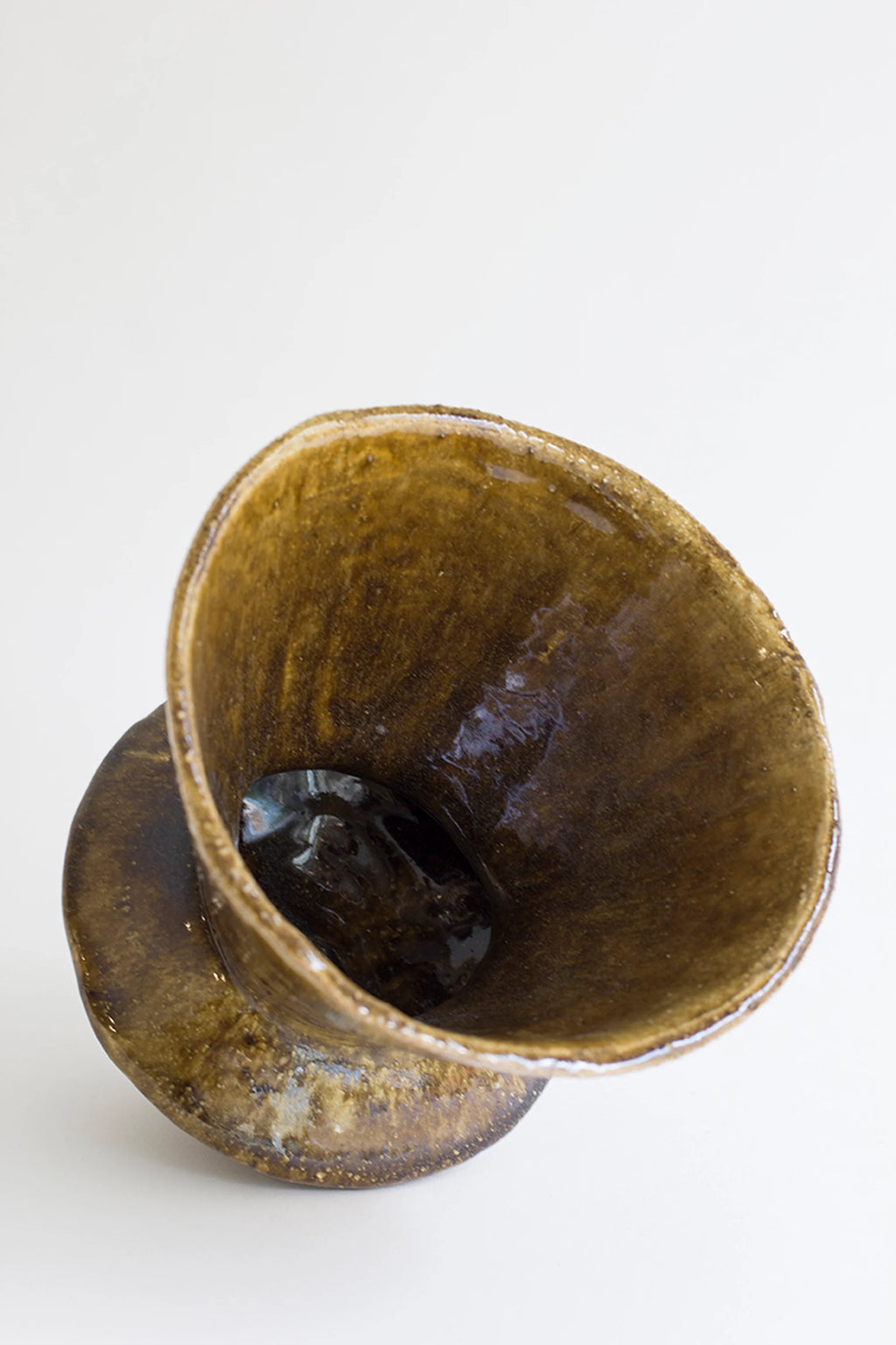 Canoa Lab Arq 010 Vase, an overhead view looking into the deep, conical opening of the handcrafted ceramic vase, revealing its glossy dark brown interior and textured surface, on a white background.