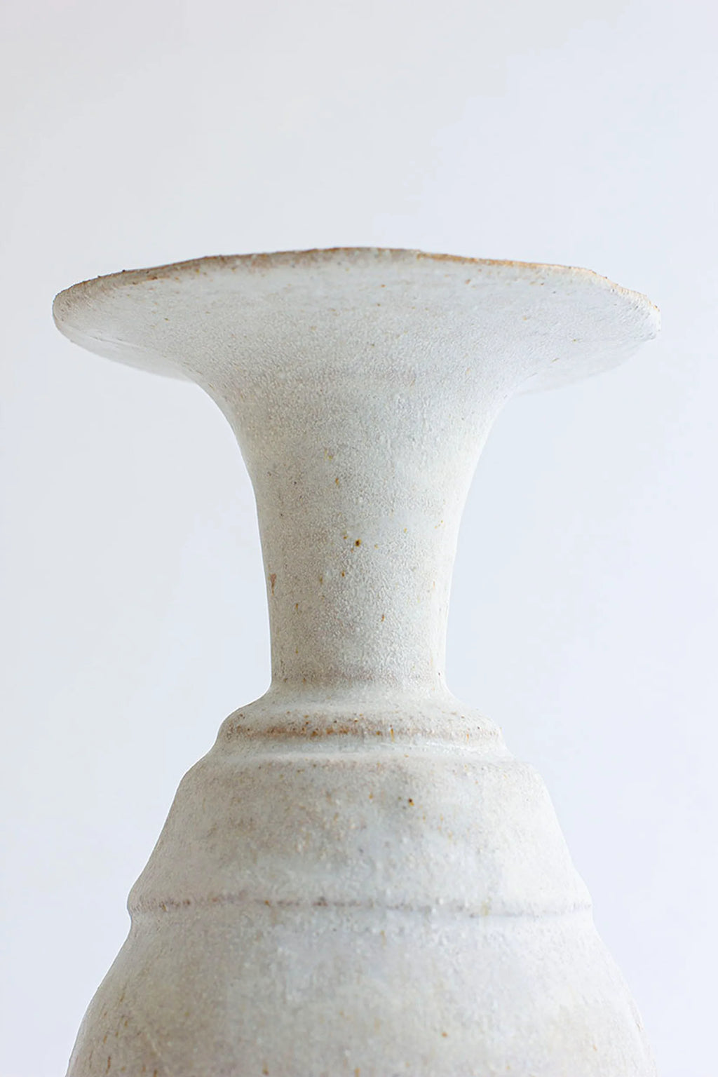 Canoa Lab Arq 011 Vase, a handcrafted unglazed ceramic vase in a natural cream color with a porous, textured stoneware finish and subtle brown speckles. It features a distinctive flared rim and an elegant trumpet neck, creating a sculptural, organic modern silhouette. Perfect for wabi-sabi or rustic minimalist shelf styling and contemporary home decor.
